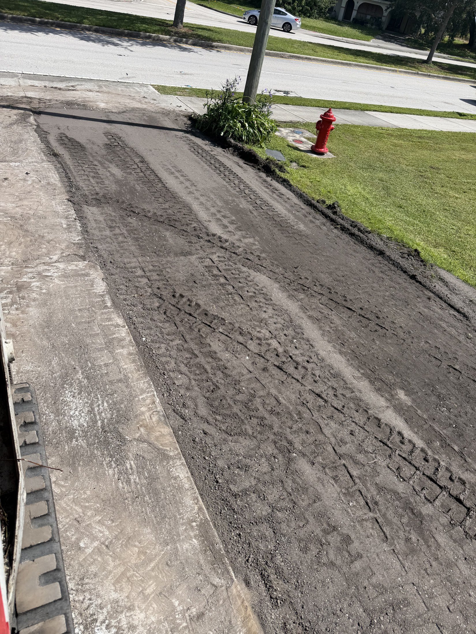 Graded ground with equipment tracks along a residential property.