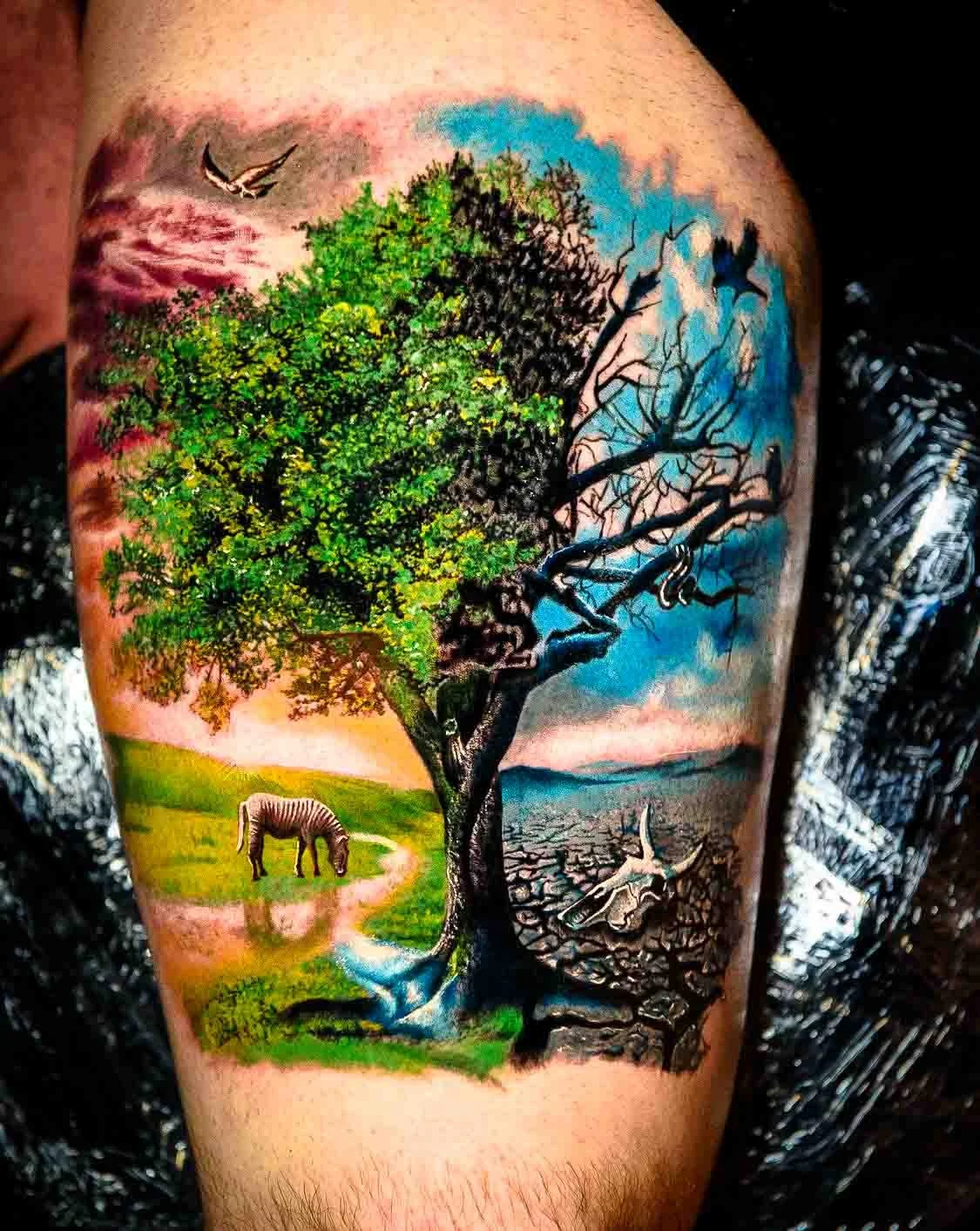 Color realism tree tattoo contrasting green leaves and a living landscape with bare branches and cracked earth.