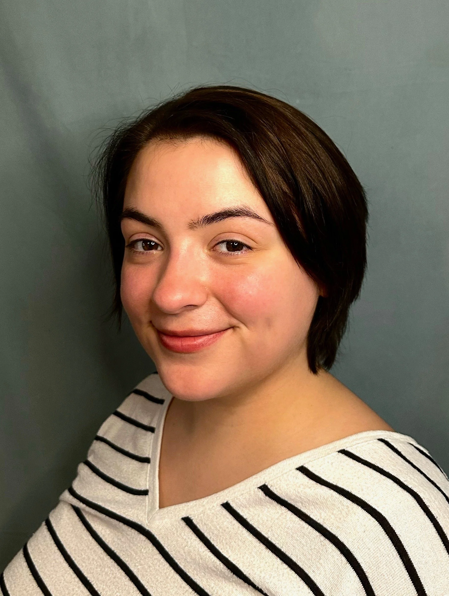 Close-up portrait of a female professional tarot reader with short dark hair wearing a black-and-white striped top