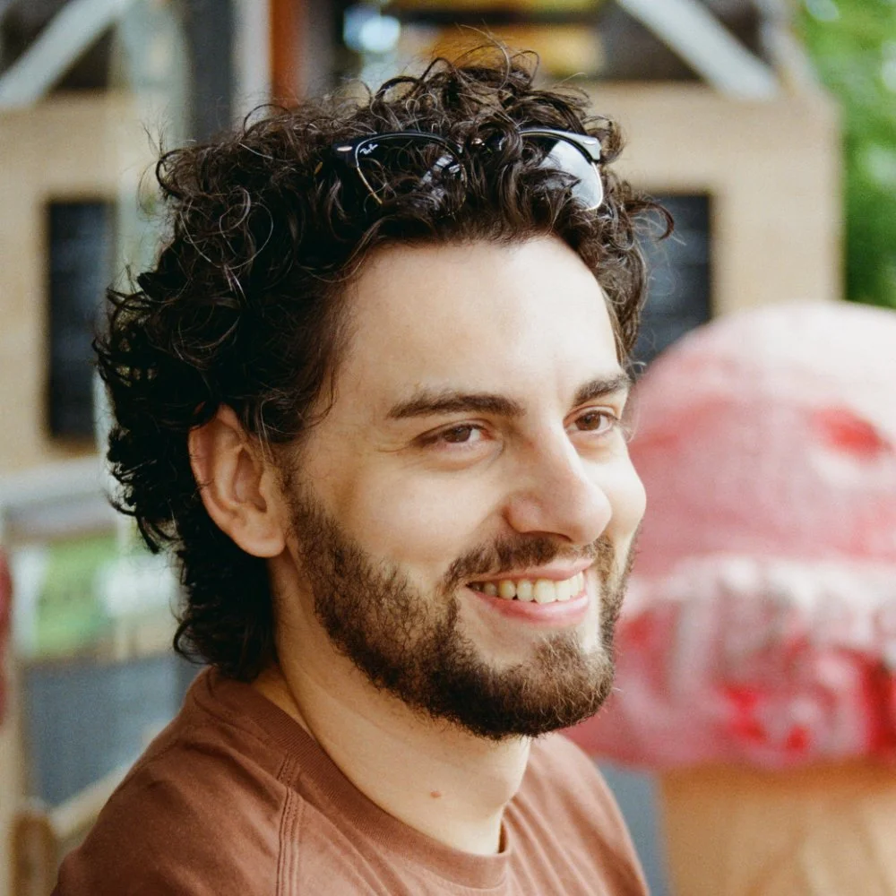 Smiling bearded man with curly hair and sunglasses resting on his head