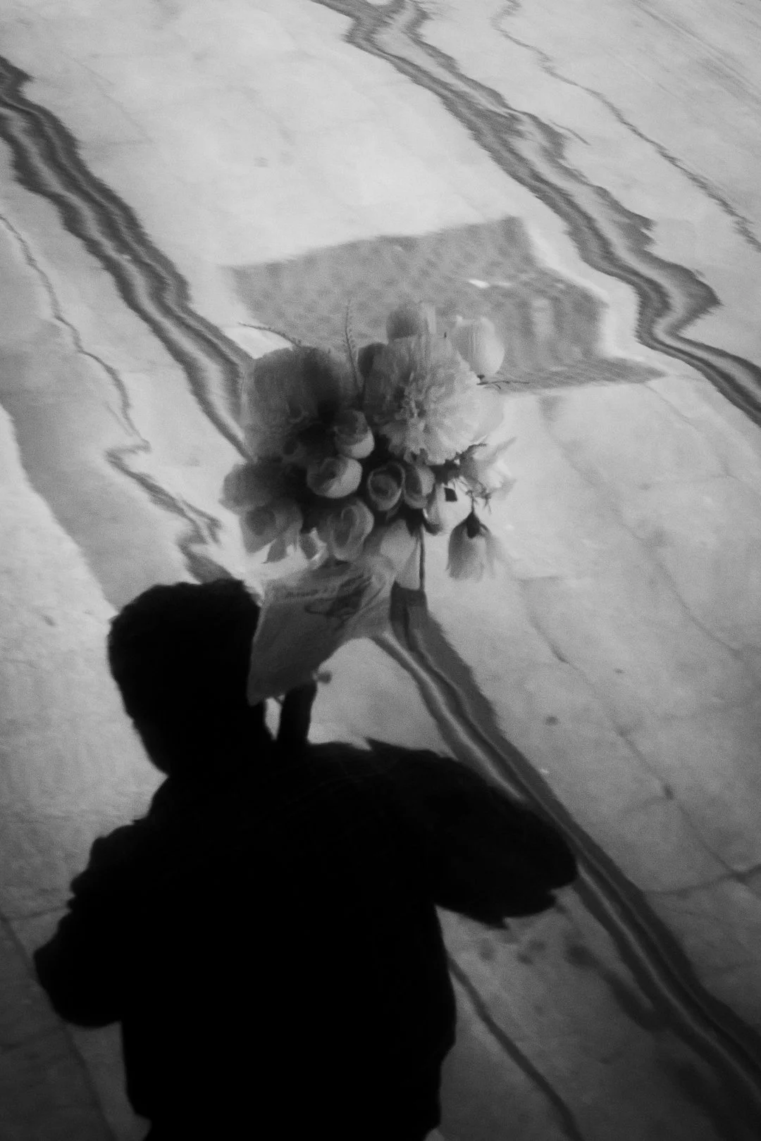 Black-and-white photo of a person holding a bouquet of flowers.