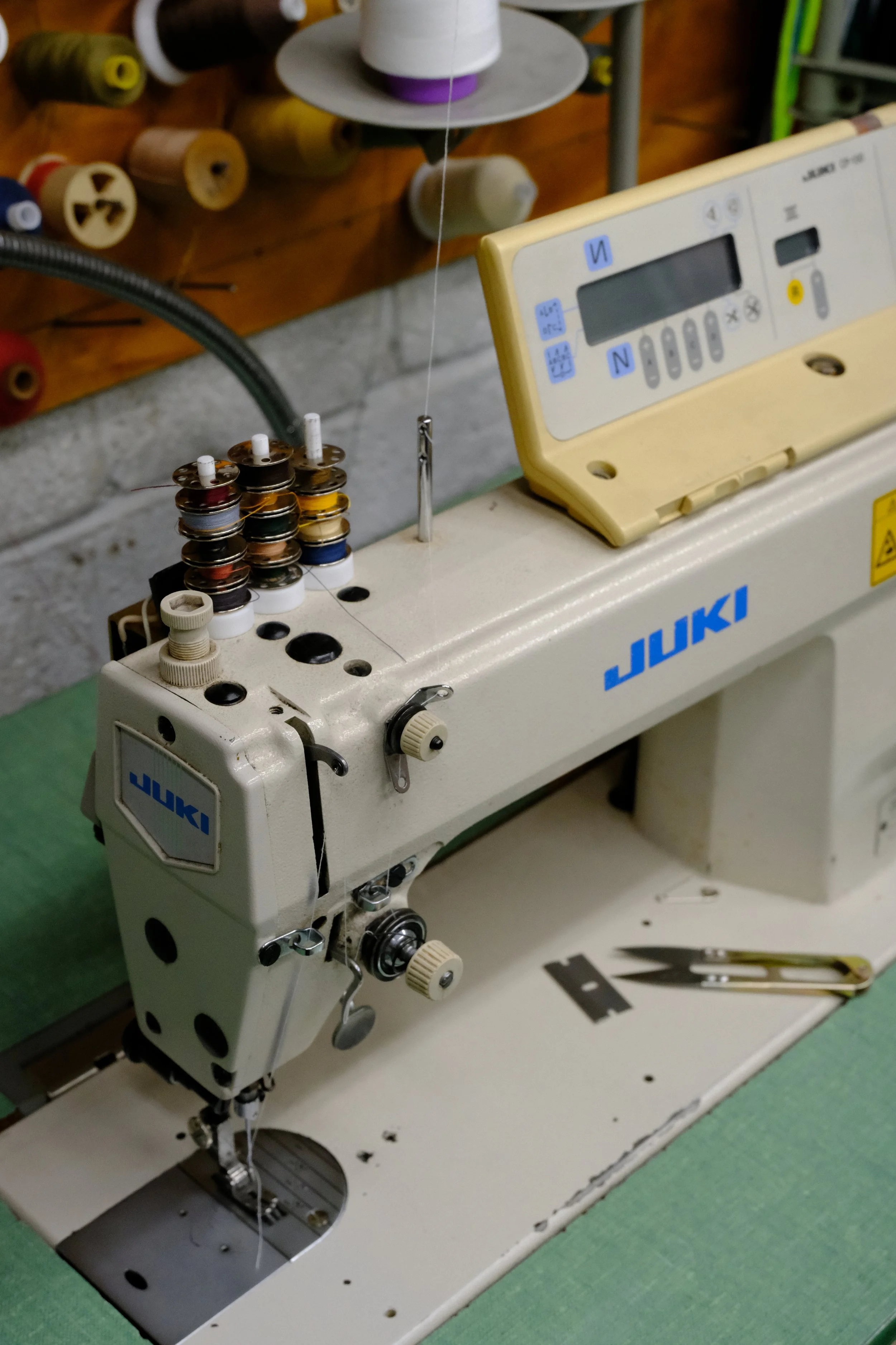 Juki industrial sewing machine with colorful thread bobbins and spools in a garment workshop