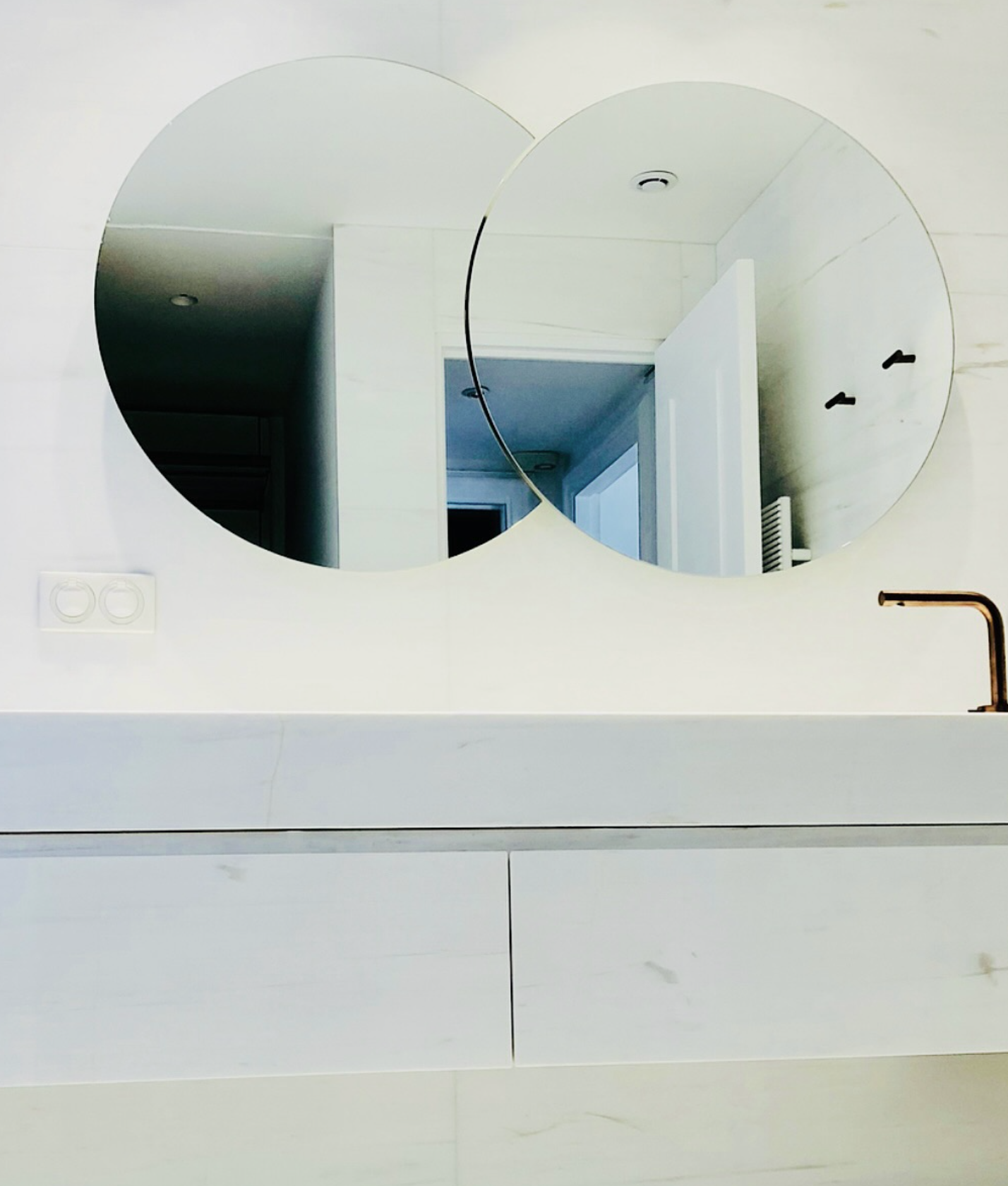 Salle de bains moderne blanche avec deux miroirs ronds, meuble-lavabo et robinet noir mat
