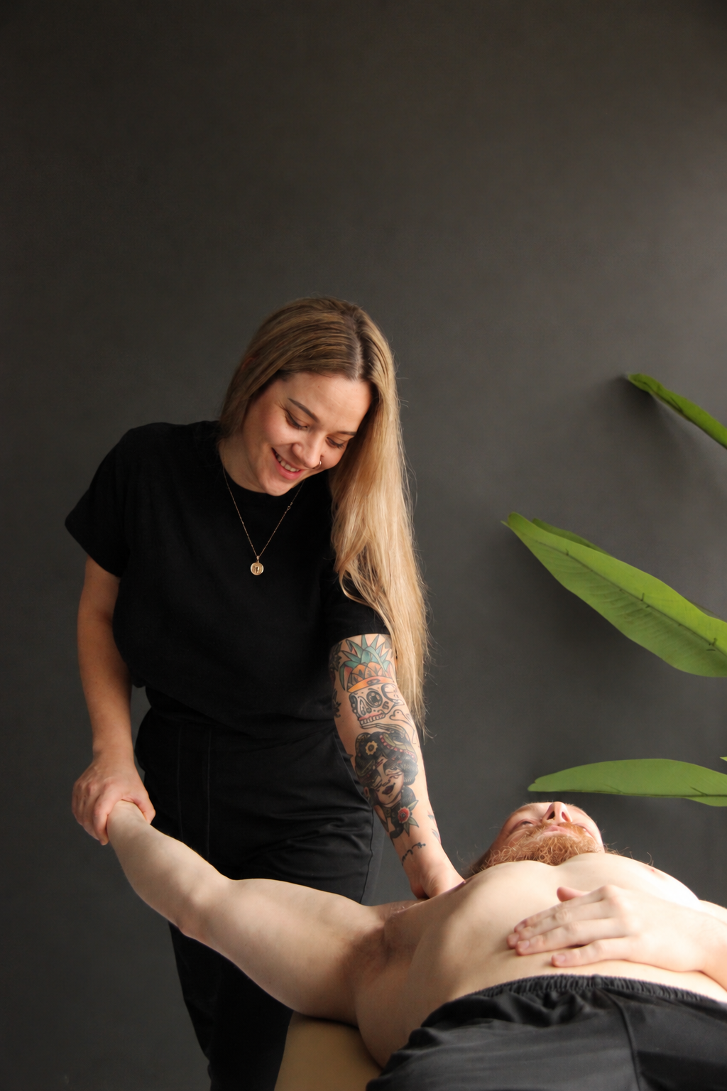 Nicole Wagner, RMT, guiding a client through an assisted arm stretch on a treatment table.