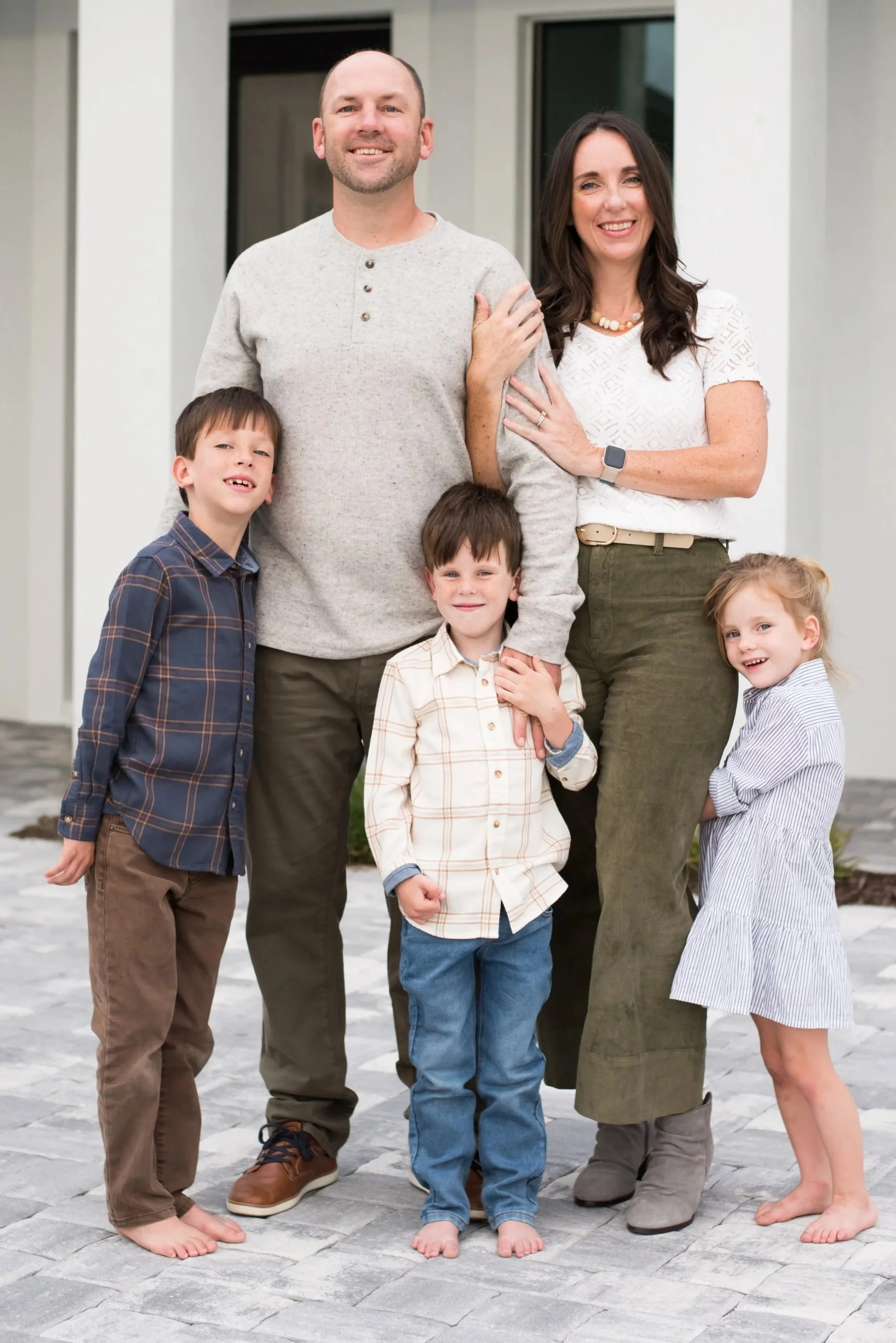 Smiling family of five posing together outside their home