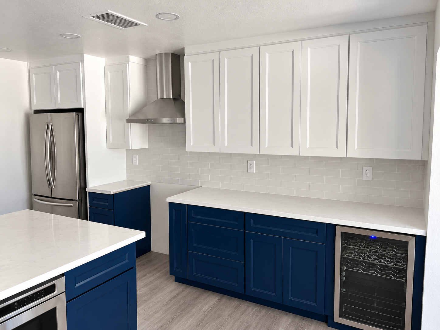 Kitchen with white upper cabinets, blue lower cabinets and tile backsplash
