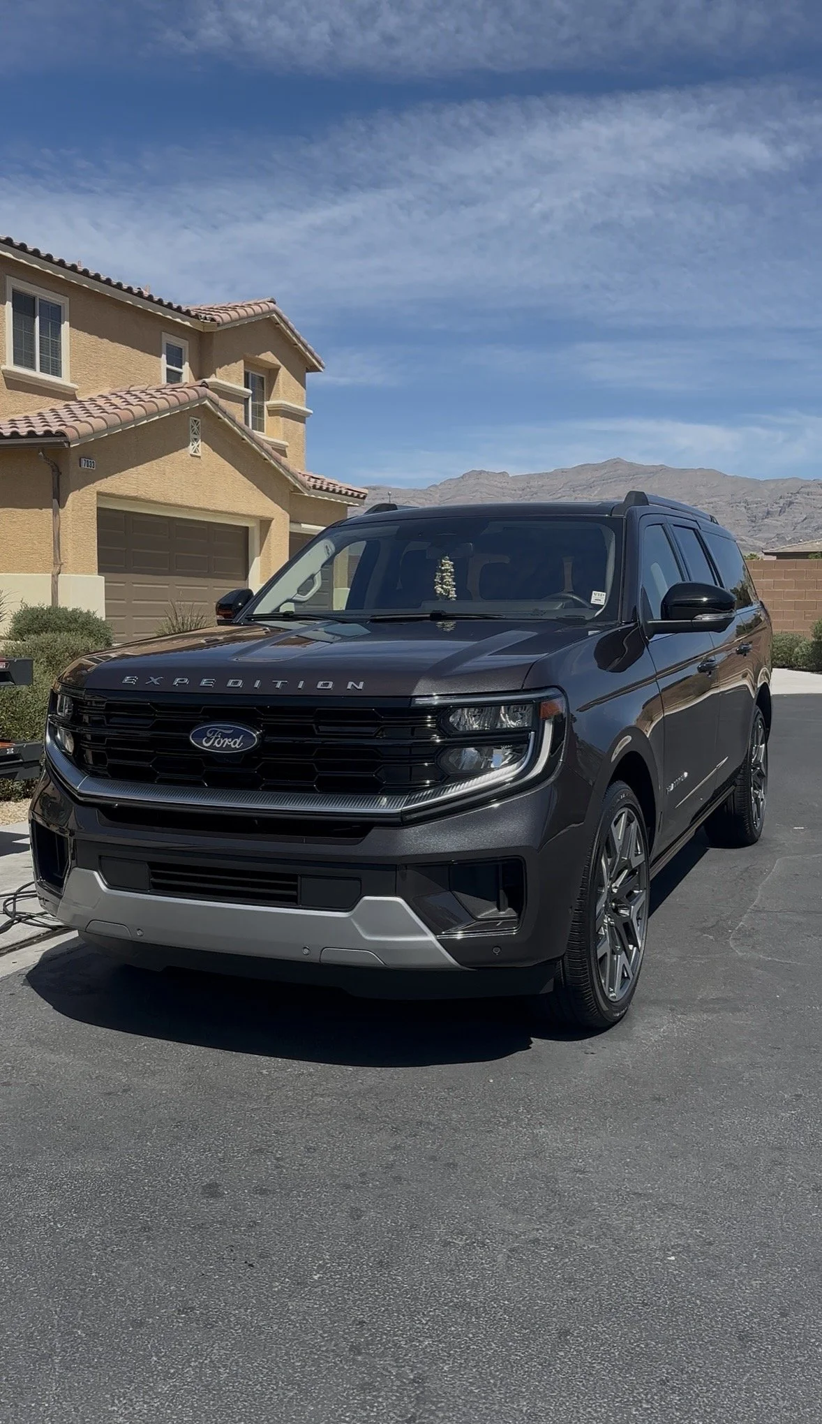Dark gray Ford Expedition SUV parked in a suburban driveway with mountains in the background
