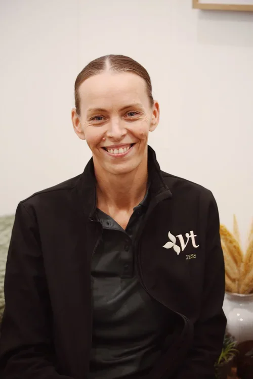 Smiling woman wearing a black jacket with a white embroidered logo