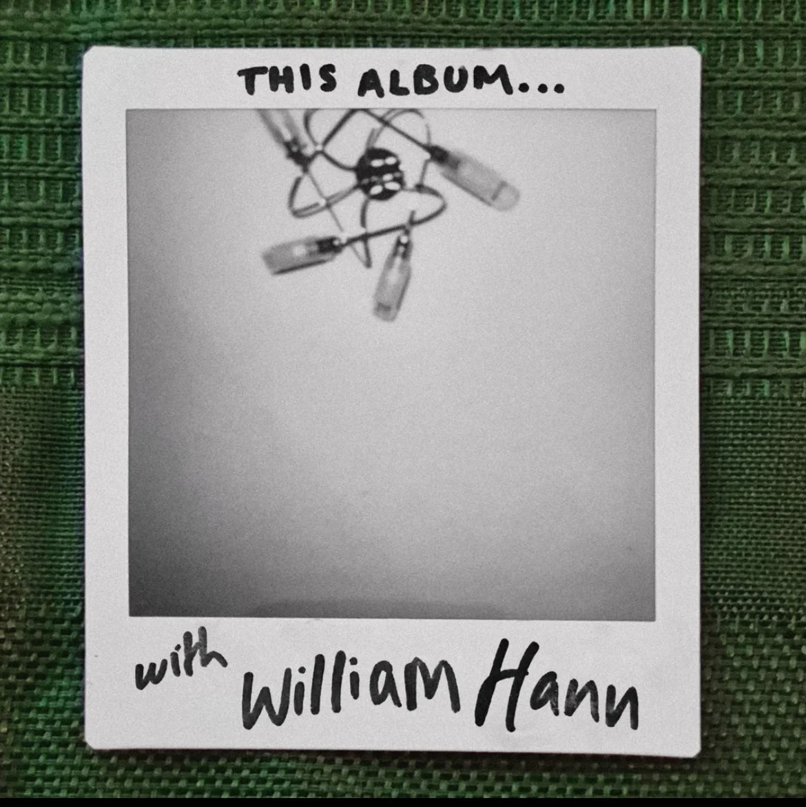 Polaroid-style photo labeled “THIS ALBUM...” and “with William Hann,” showing a small atom-shaped object with dangling capsules.