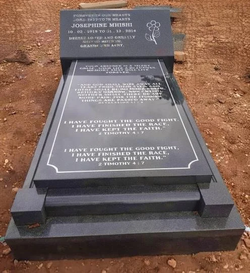 Black granite tombstone for Josephine Mhishi, featuring a floral engraving, Christian scripture, and stepped base in reddish soil.