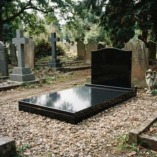 Black granite cemetery grave with upright headstone surrounded by weathered tombstones and trees