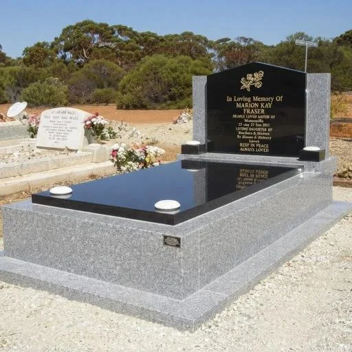 Polished black granite memorial headstone and grave in an outdoor cemetery