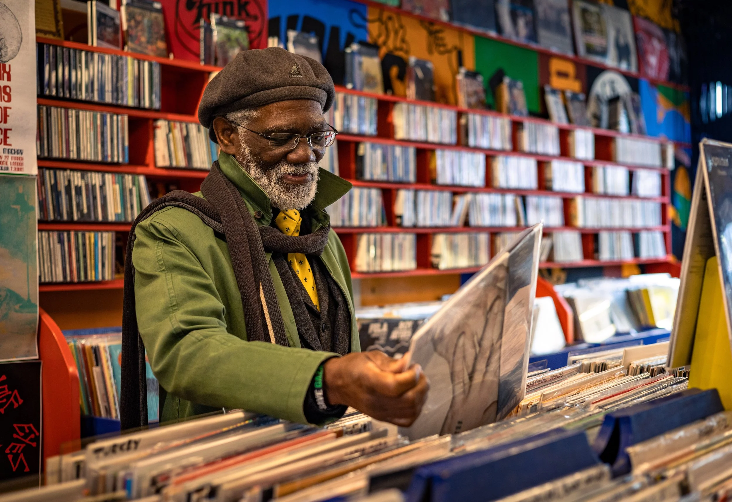 Man browsing vinyl records in a colorful record store. Photo by Jon Rees.