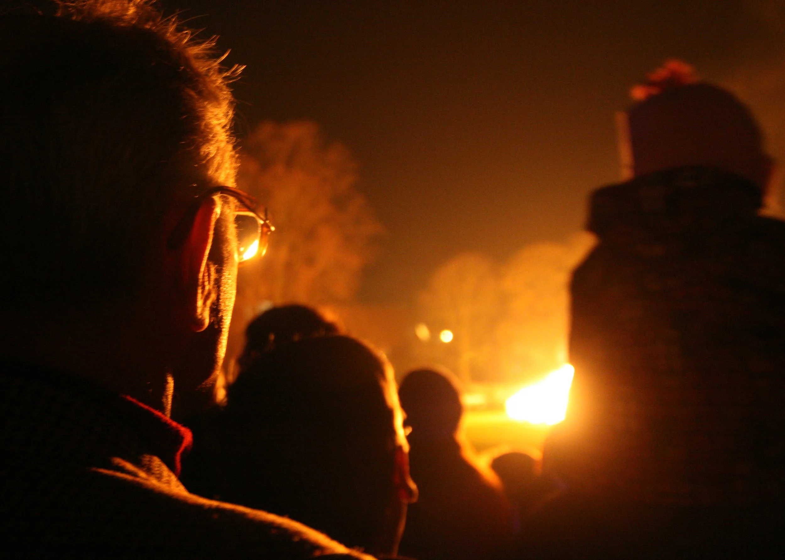 Silhouetted concert audience watching a brightly lit performer on stage in warm orange light. Photo by Jon Rees.