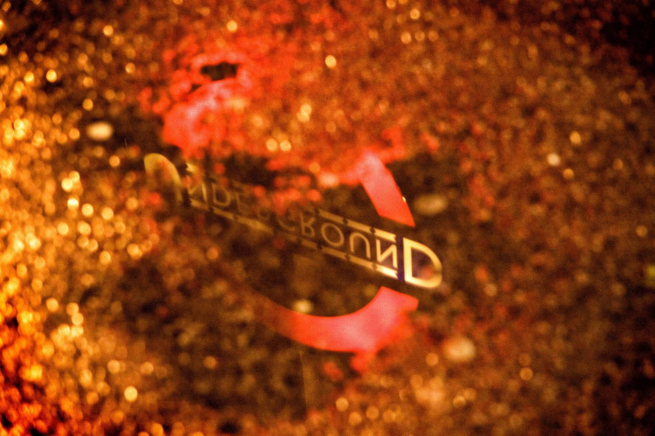 Close-up of a red satin ribbon with a black-and-white "BONUS" label on a glittering golden background. Photo by Jon Rees.