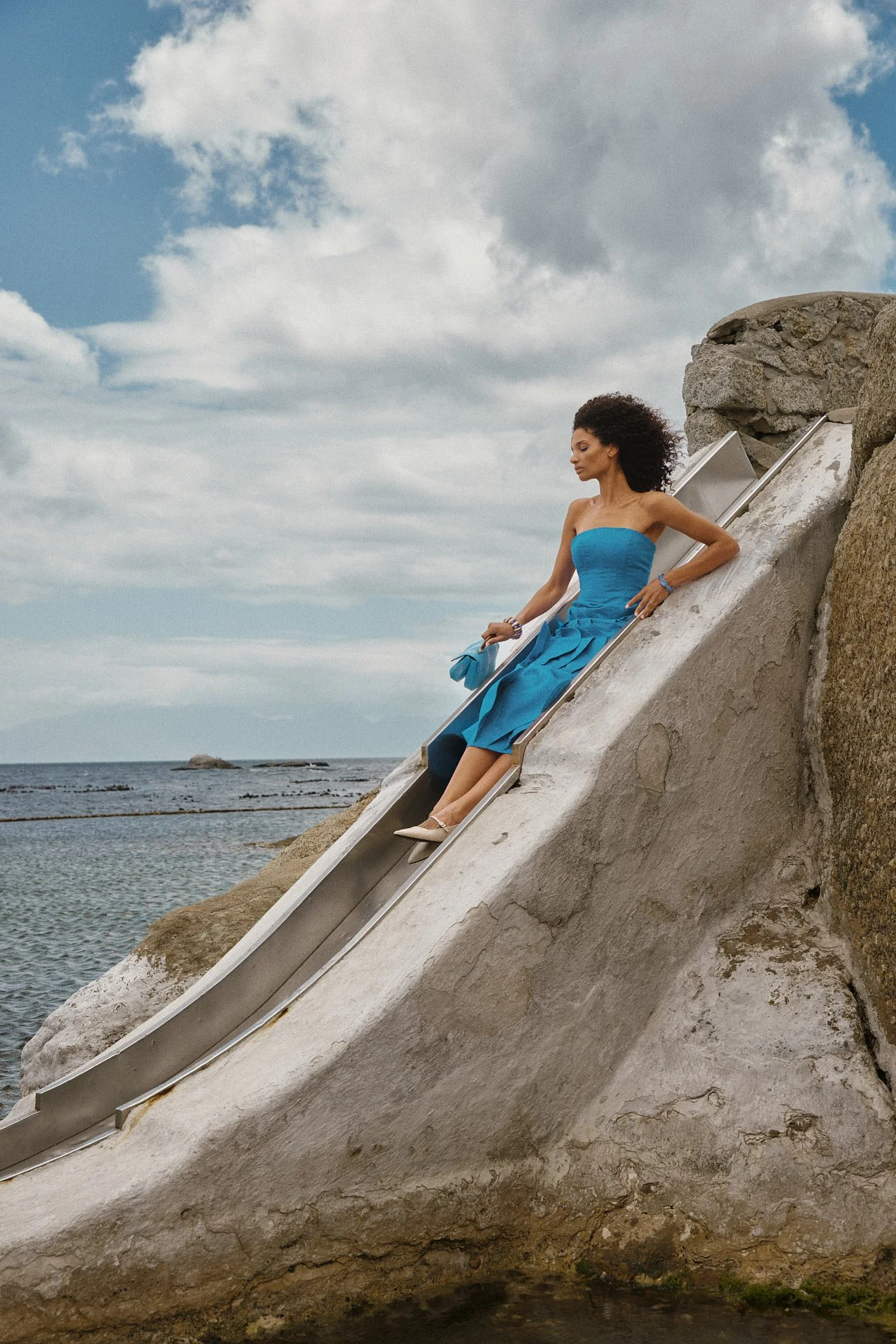 image of woman in blue dress on a slide by the ocean