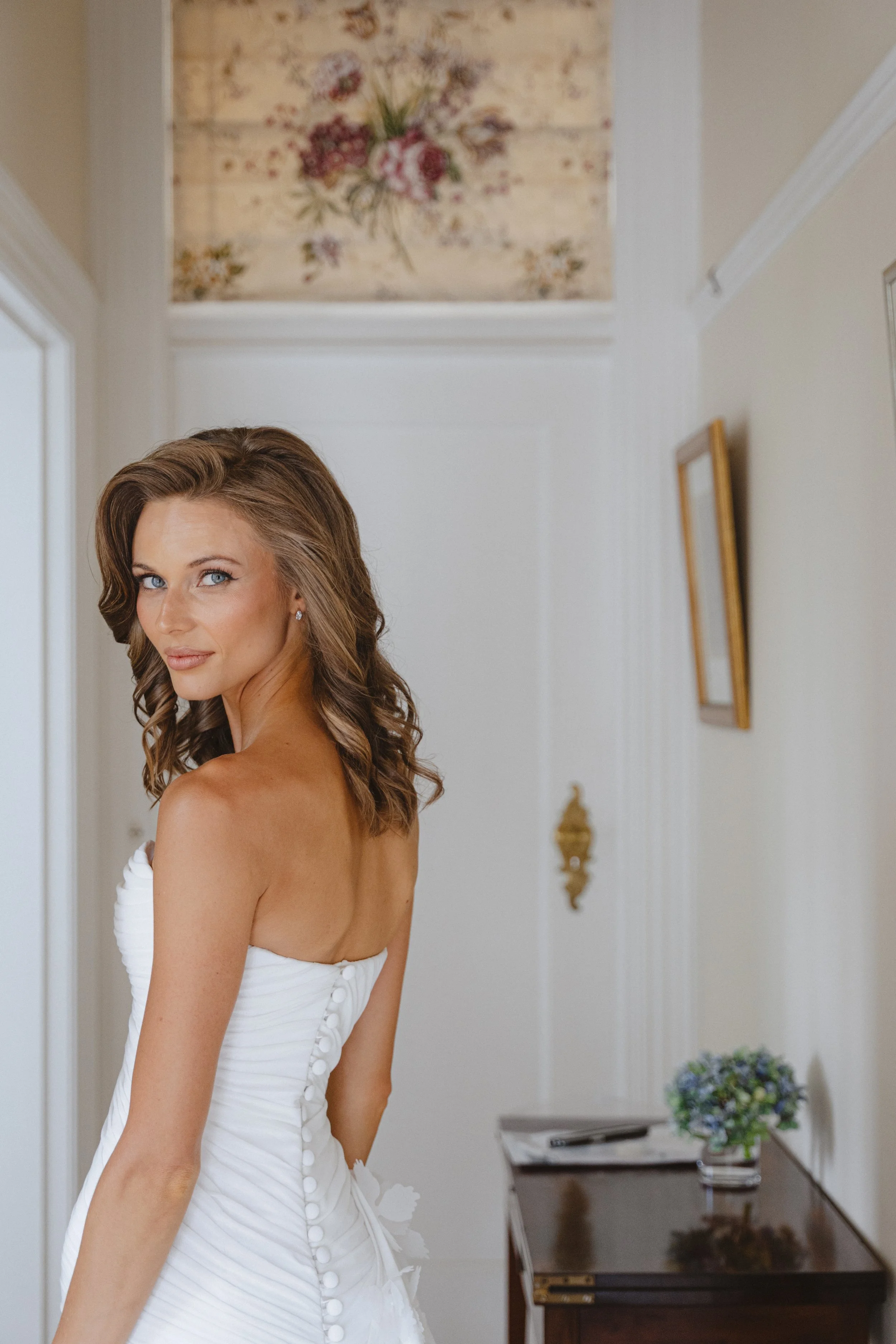 Bride in a white wedding dress with curled hair posing indoors