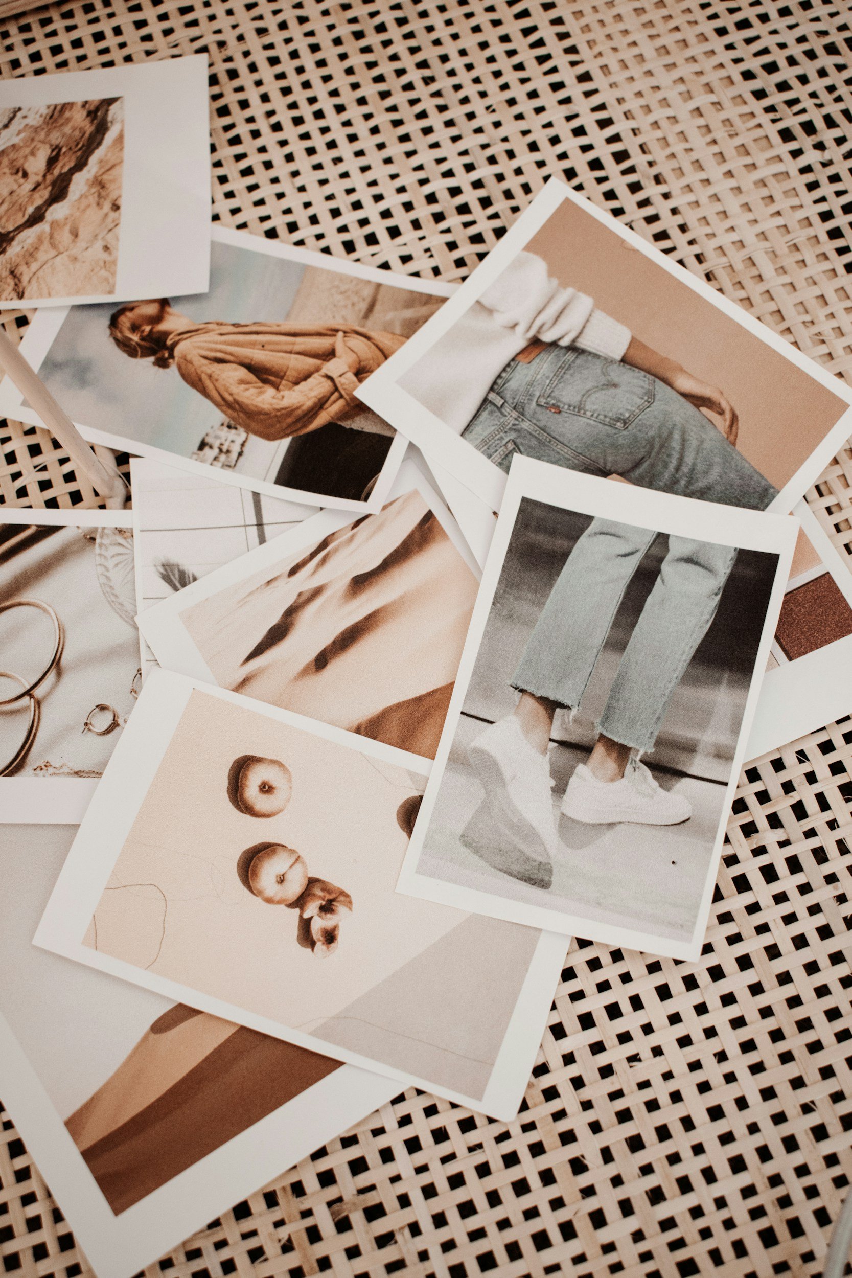 Overlapping fashion photographs and art prints arranged on a table for selection by brand team.