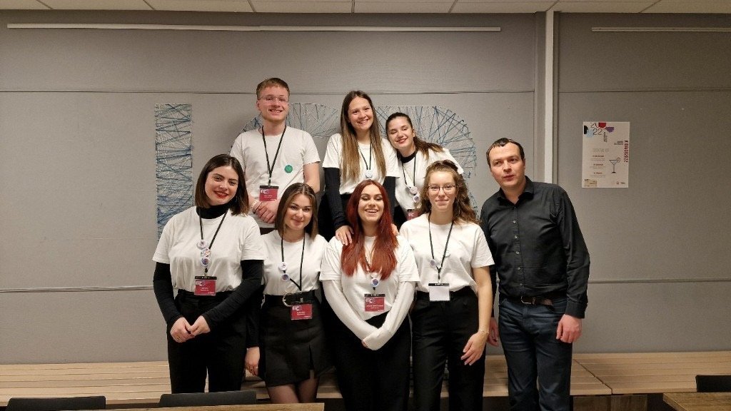 Photo de groupe de huit personnes portant des badges, réunies dans une salle de conférence.