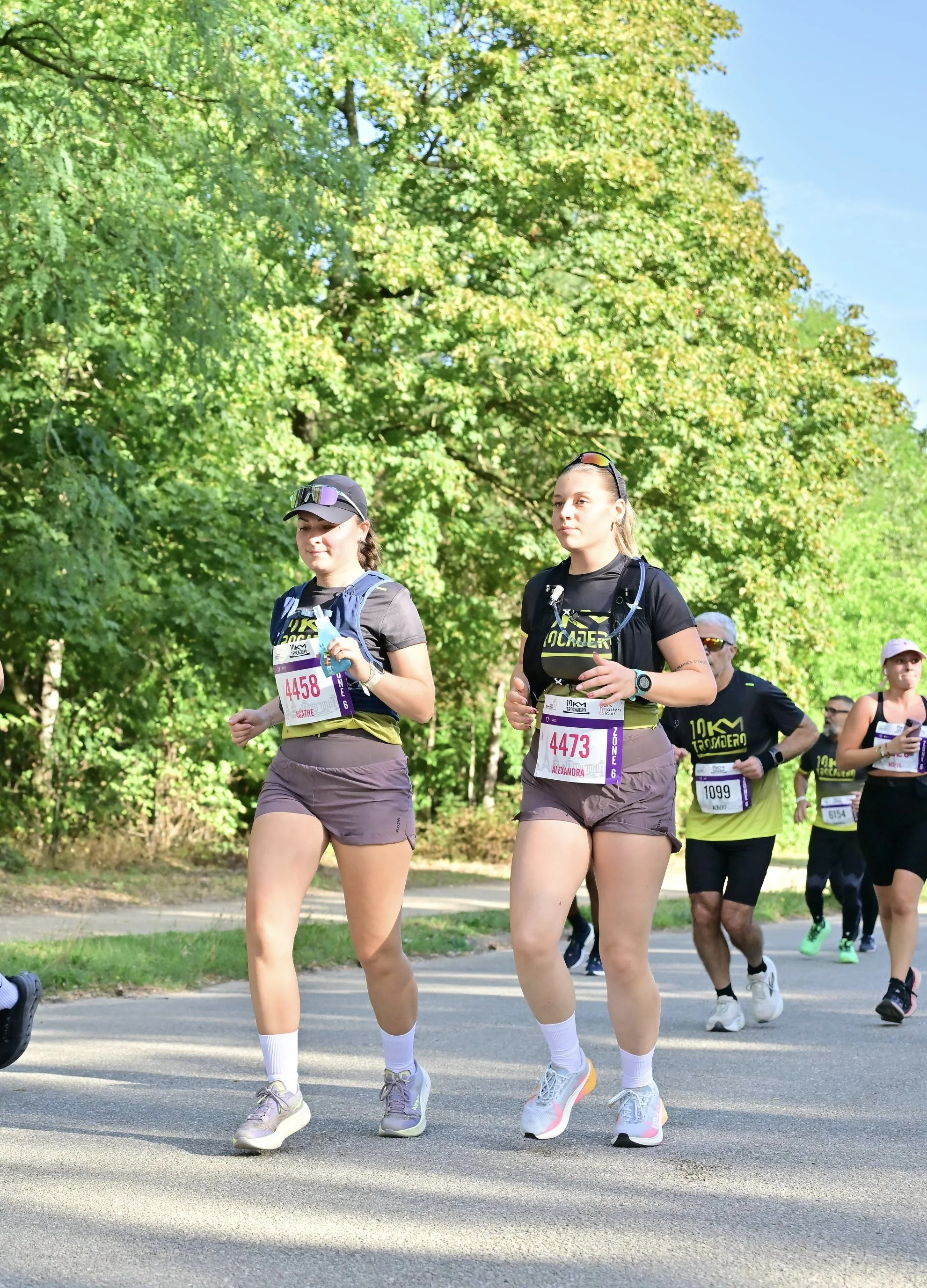Participants courant un 10 km sur une route bordée d’arbres.