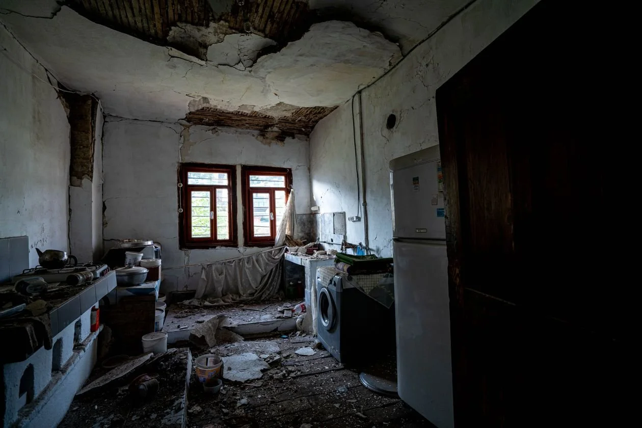 Abandoned kitchen before renovation — ruined cabinets, debris, and a collapsed ceiling