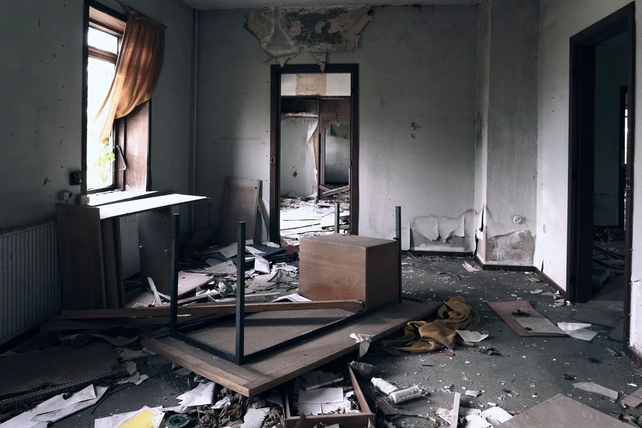 Trashed living room before renovation — overturned furniture and debris across the floor