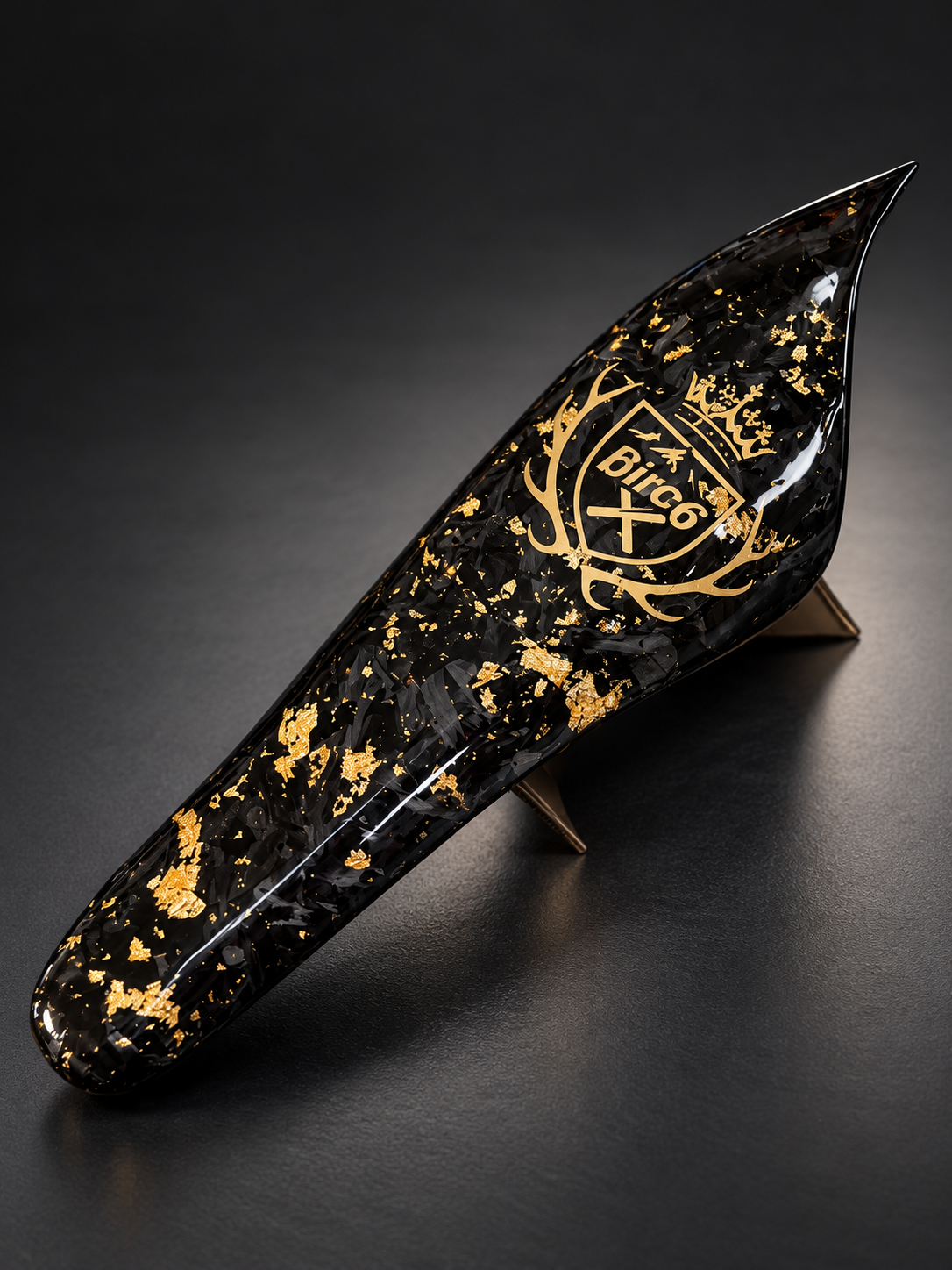 Black glossy ocarina with gold flecks and ornate BirCo emblem displayed on a stand