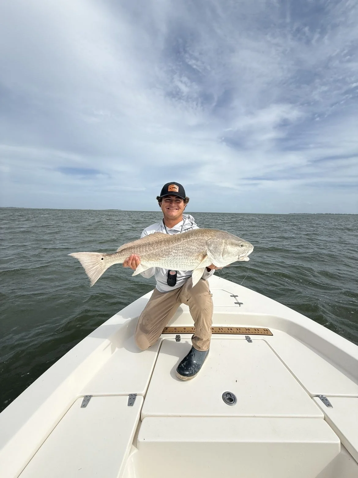 Angler holding a large redfish on the bow of a boat in open water