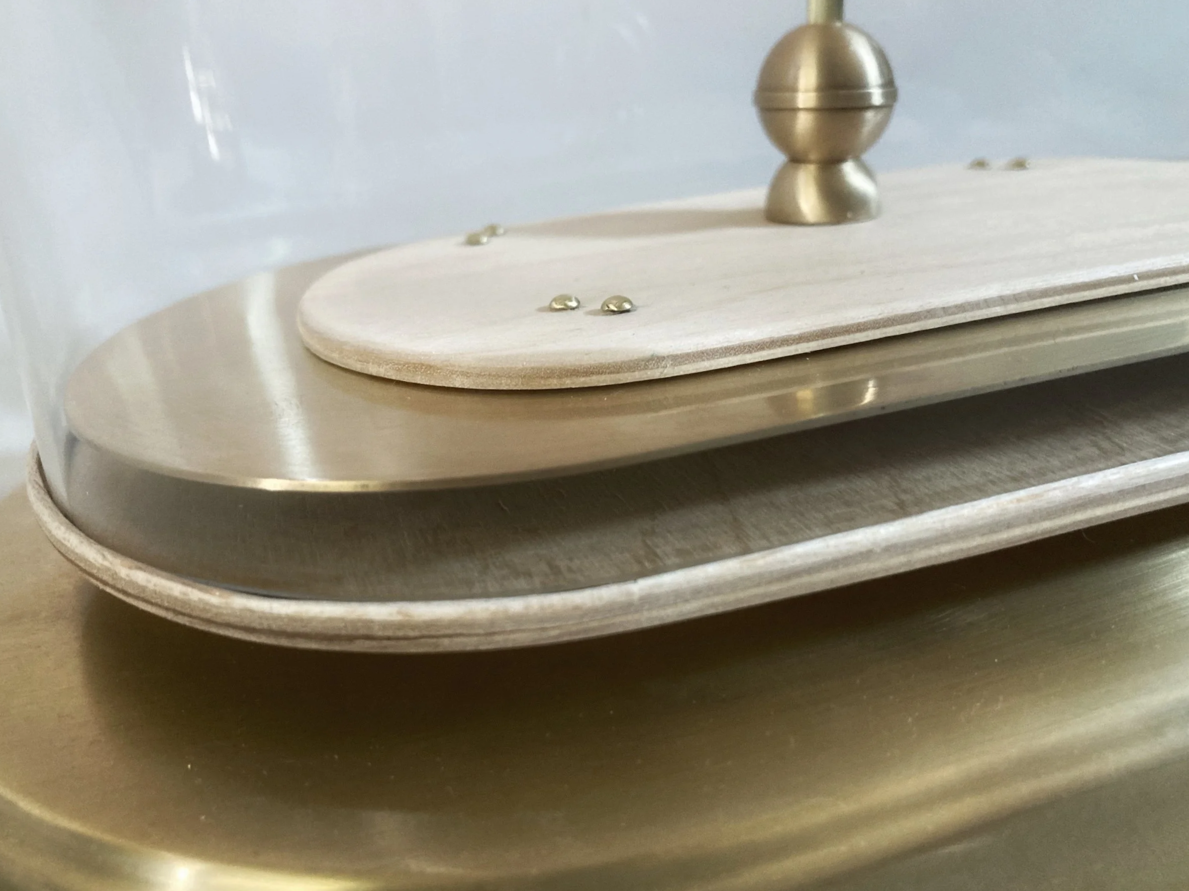 Close-up of a vintage brass record player with a wooden tonearm base and turntable platter.