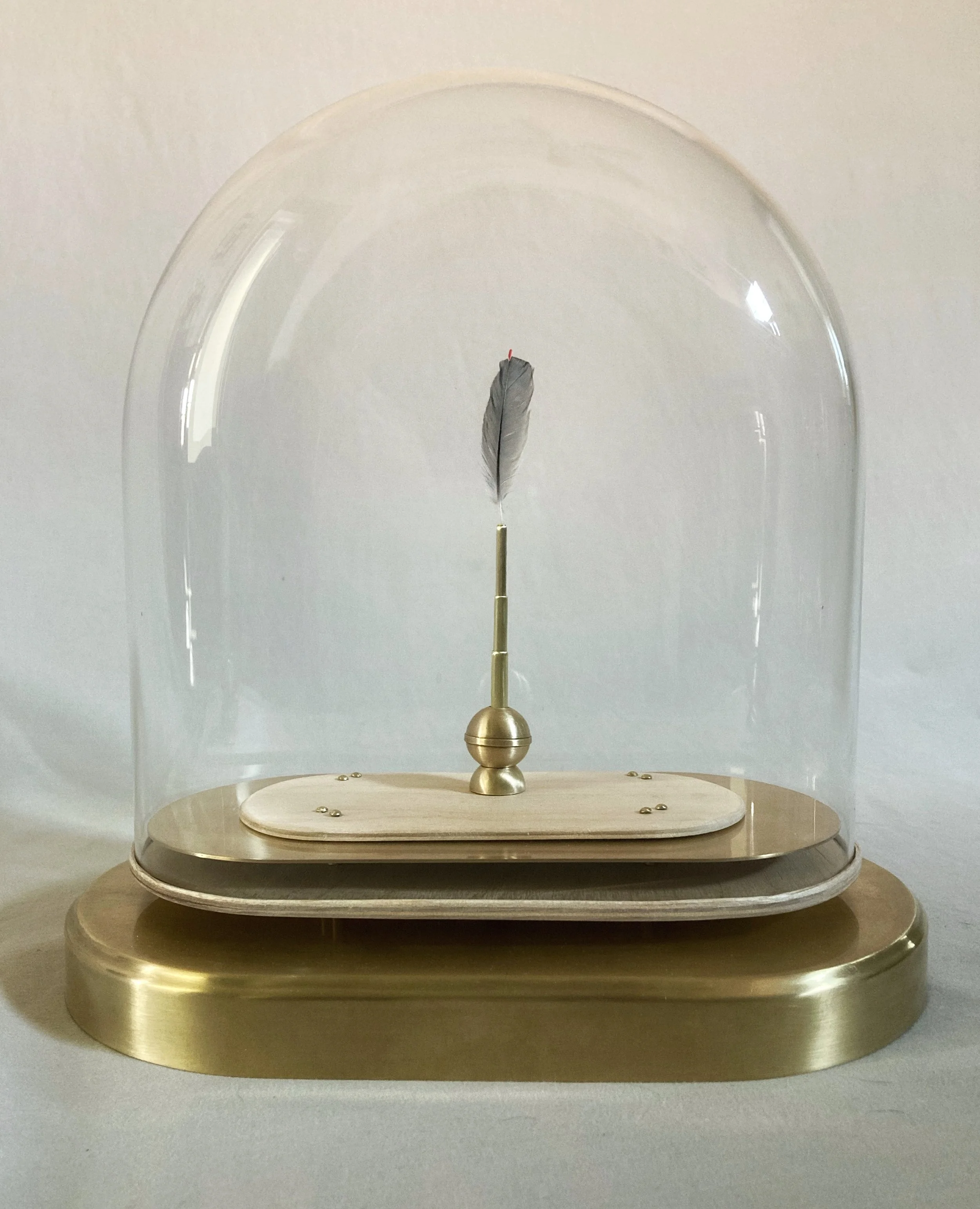 Antique gold pendulum with a feather suspended inside a glass dome