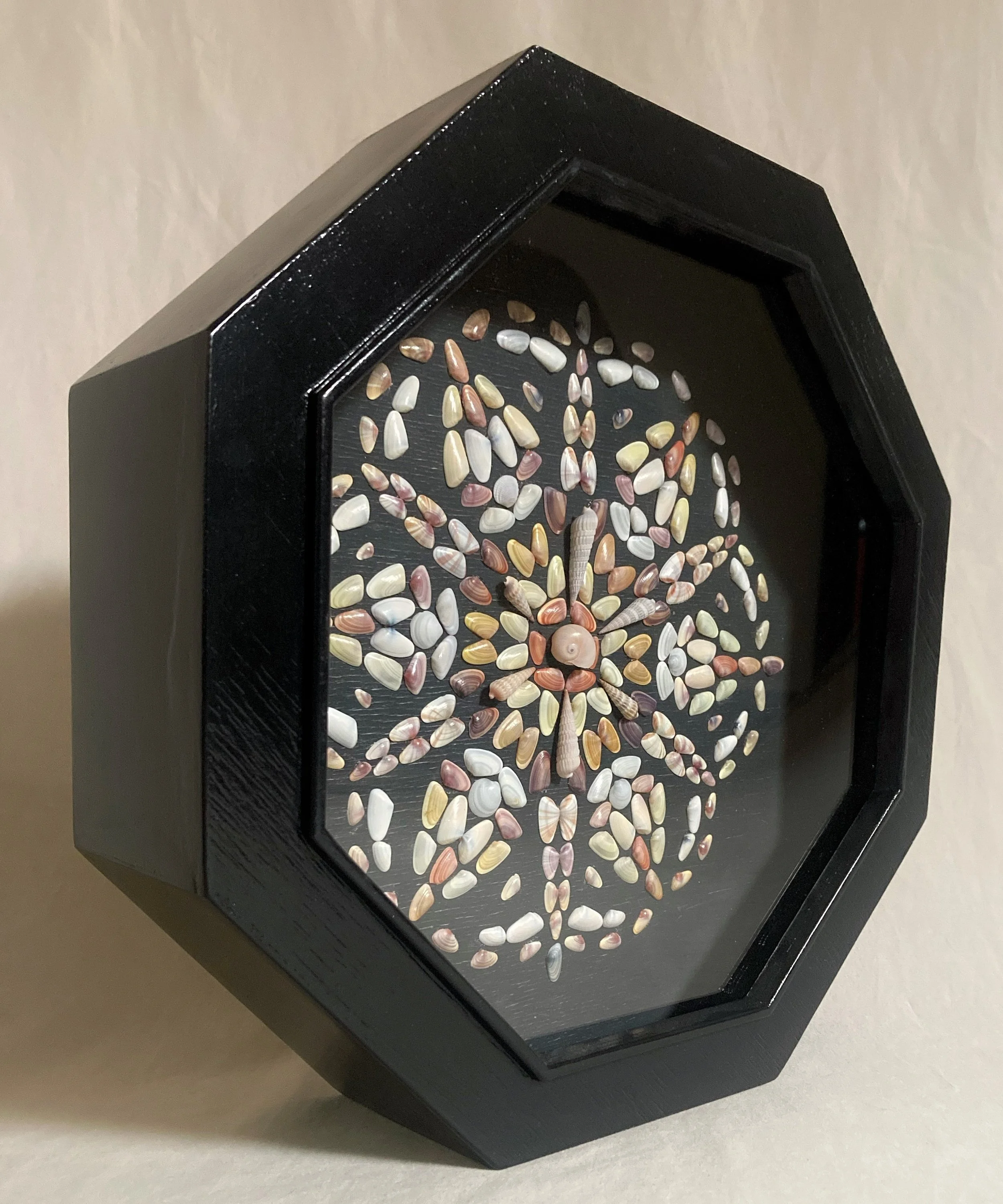 Framed black-and-white seashell mosaic depicting a seahorse on a dark background.