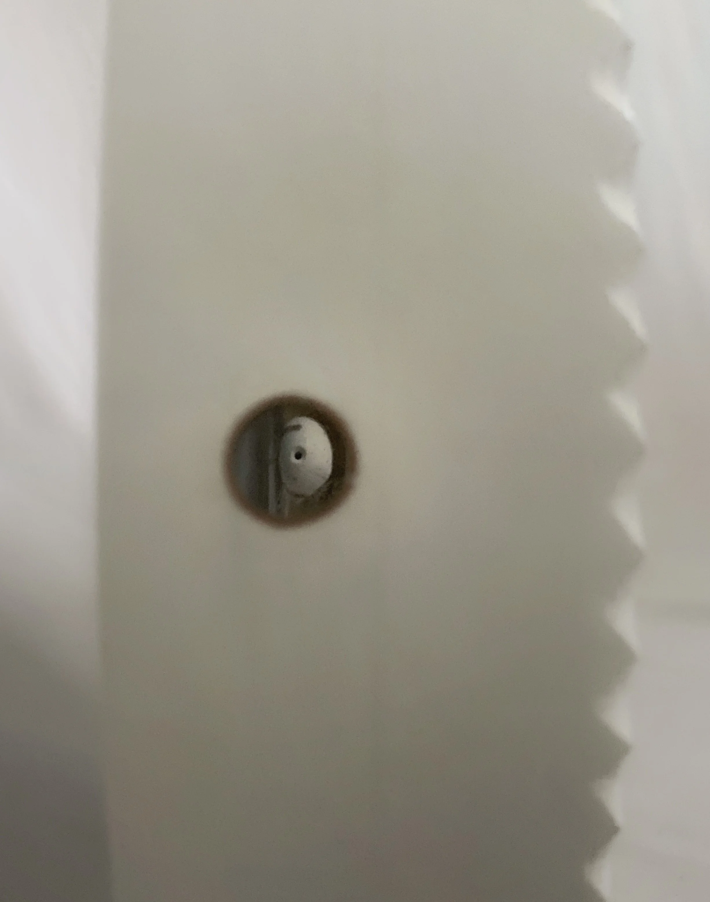 Close-up of a white electrical outlet plate with a dark, damaged circular opening