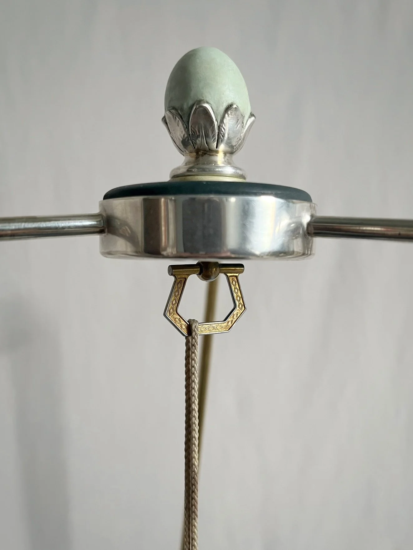 Close-up of a vintage silver and brass umbrella handle with a decorative finial and braided wrist cord.