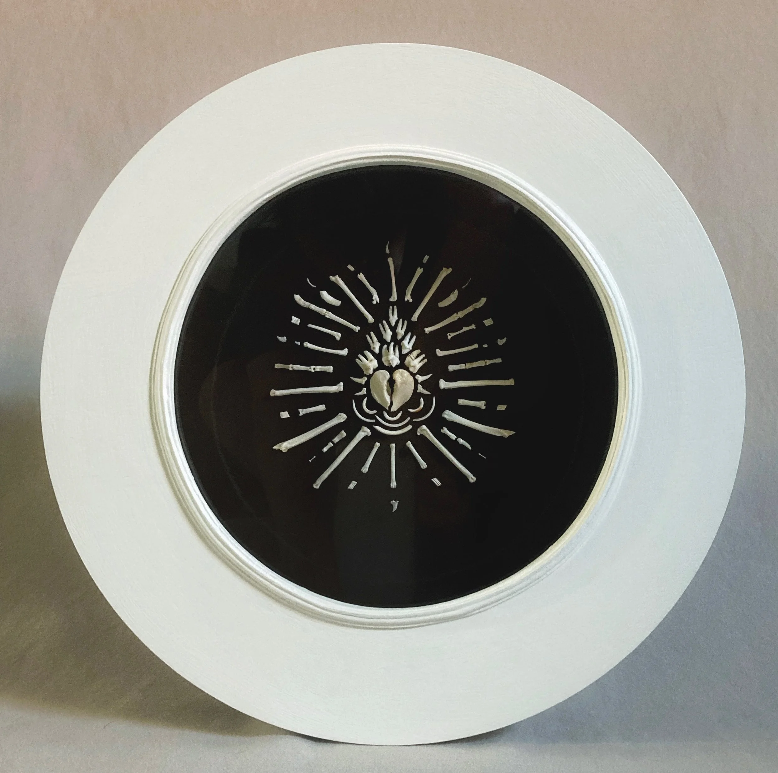 White skeleton-shaped cake decoration arranged on a black round cake with a white frosting border