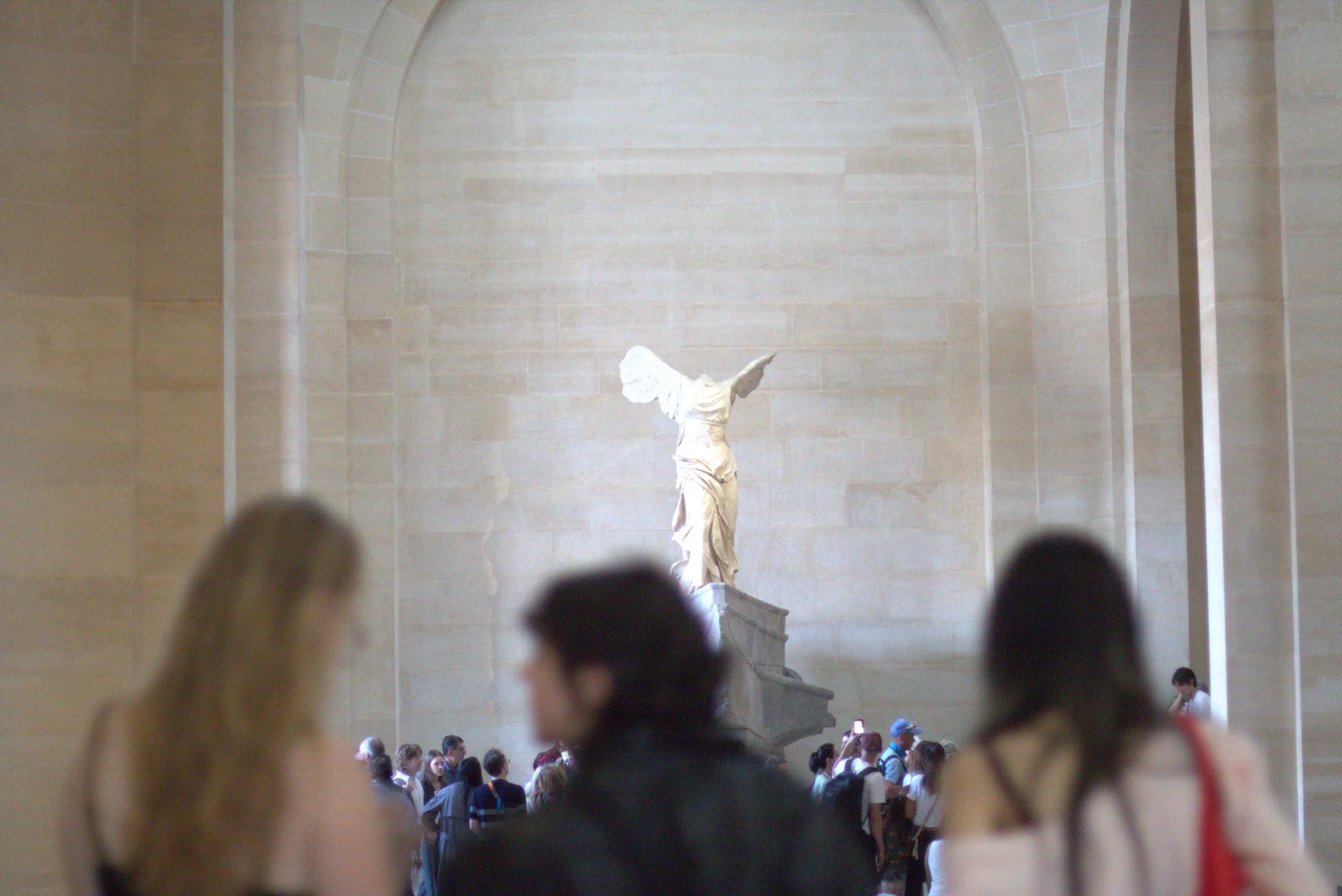 Winged Victory of Samothrace displayed in the Louvre, surrounded by museum visitors