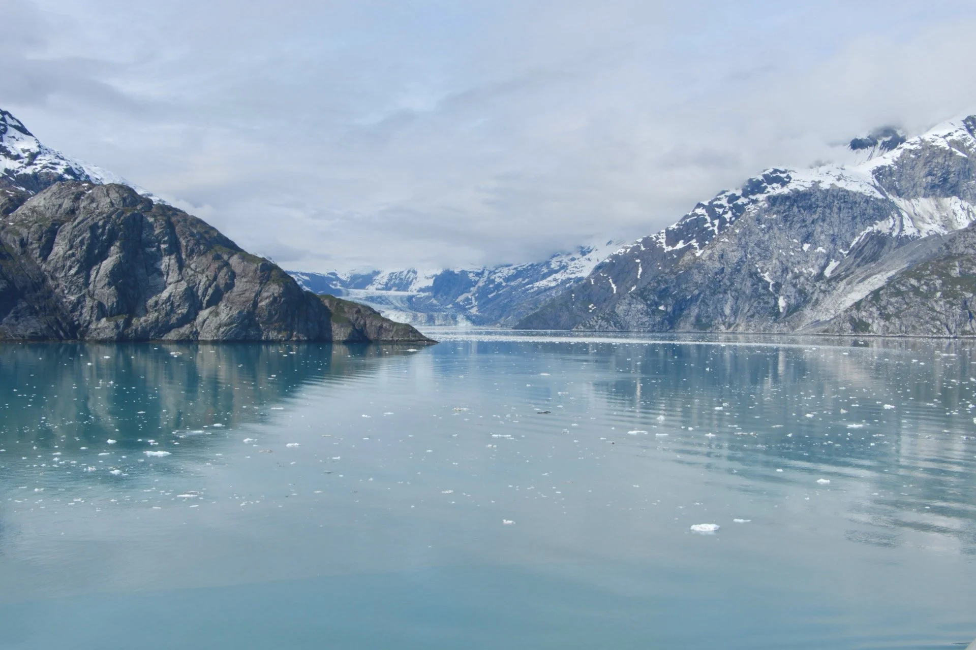 Glacier-fed turquoise fjord surrounded by rugged, snow-capped mountains and floating ice chunks