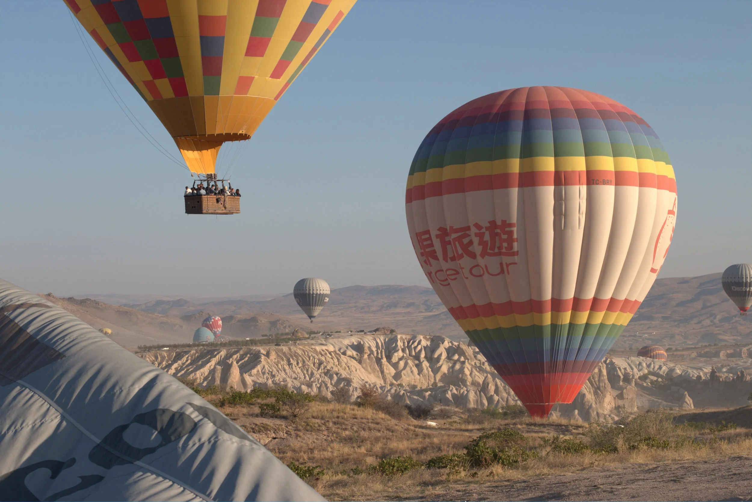 Colorful hot air balloons flying over Cappadocia’s rocky landscape in Turkey.
