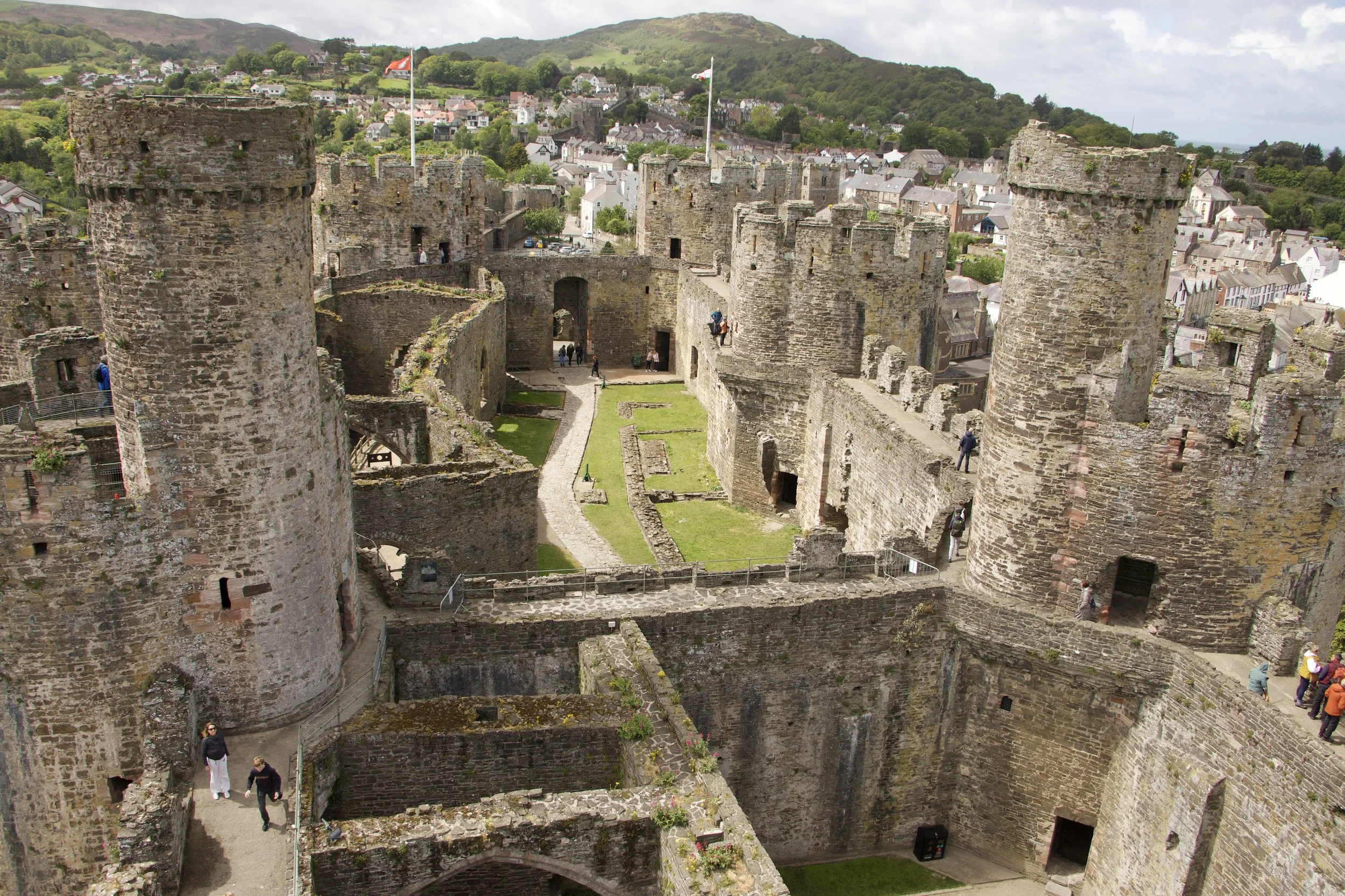 Panoramic view of Conwy Castle’s medieval stone walls and towers overlooking the Welsh town of Conwy and surrounding hills.