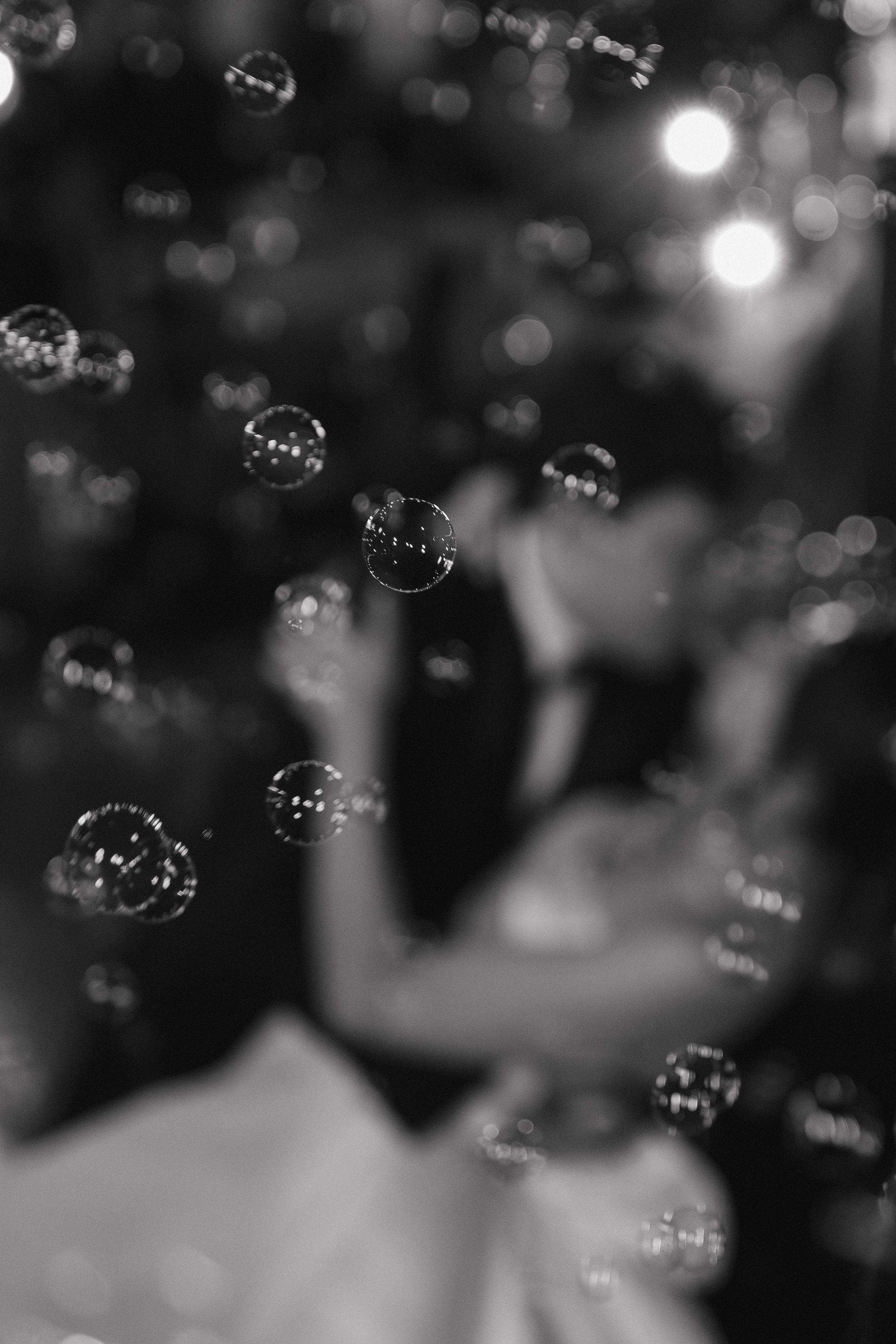 Black-and-white abstract bokeh background with blurred sparkling lights and water droplets.
