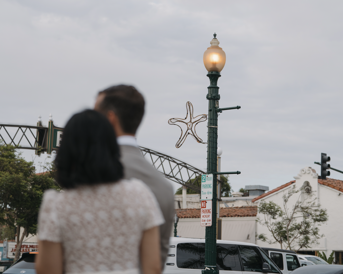 Couple walking past a vintage streetlamp with a star-shaped decoration and parking signs in a Spanish-style downtown district