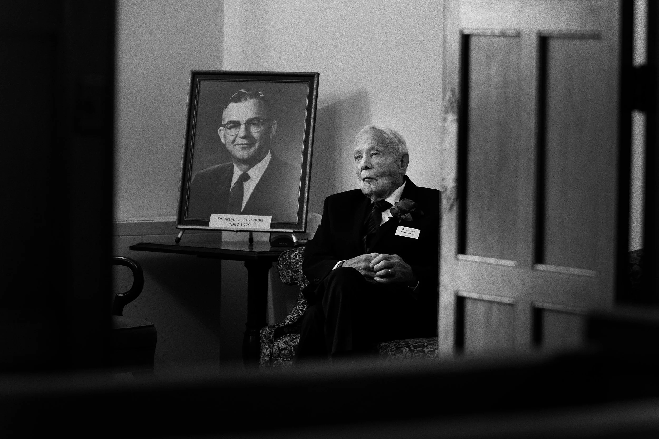 100 YEARS - Seated next to a portrait of former Senior Minister Dr. Arthur Teikmanis (1967-70), Usher Bob Cummins waits in the Narthex for the first wave of worshippers to arrive.