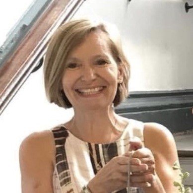 Smiling woman with short blonde hair holding a glass indoors