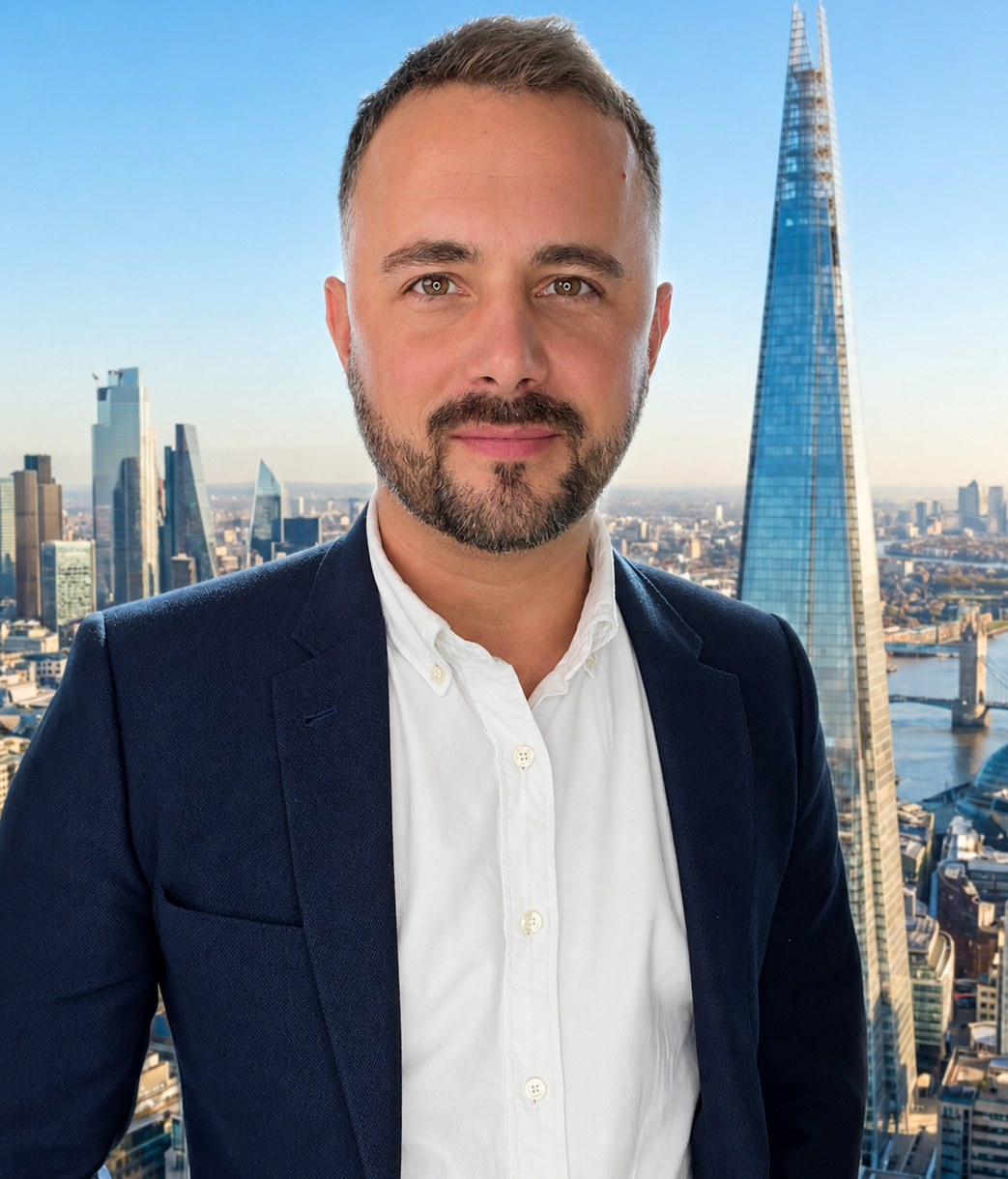 Man in a navy blazer and white shirt with London skyline and The Shard behind him