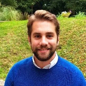 Smiling bearded man in a blue sweater outdoors in a garden