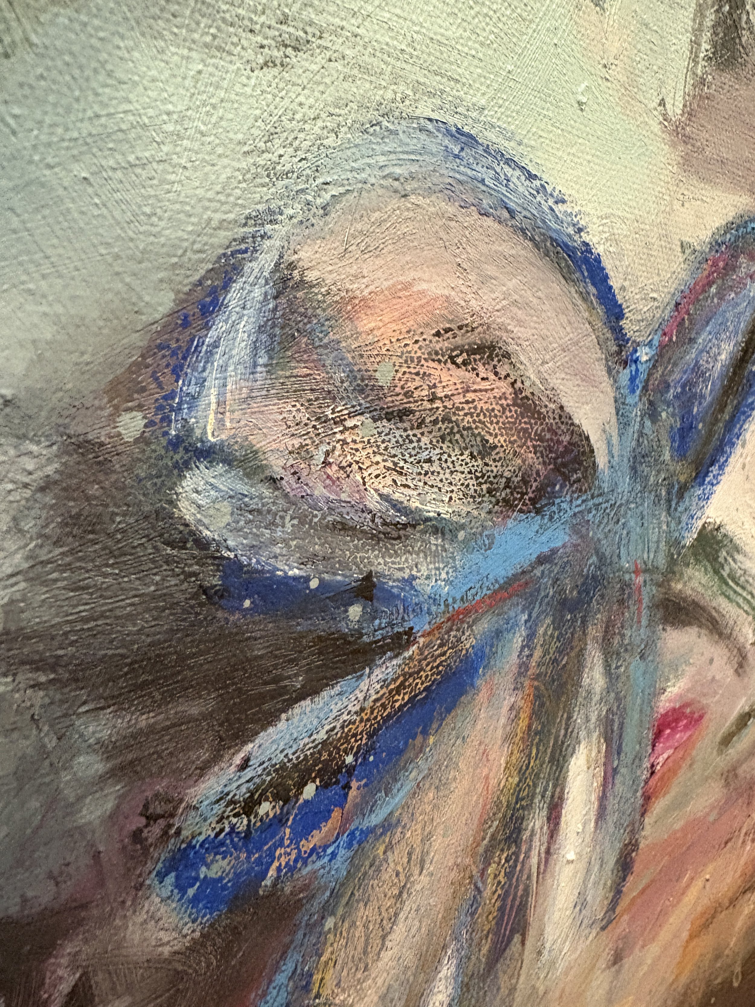 Close-up abstract painting with layered blue, pink, brown, gray, and cream brushstrokes on textured canvas