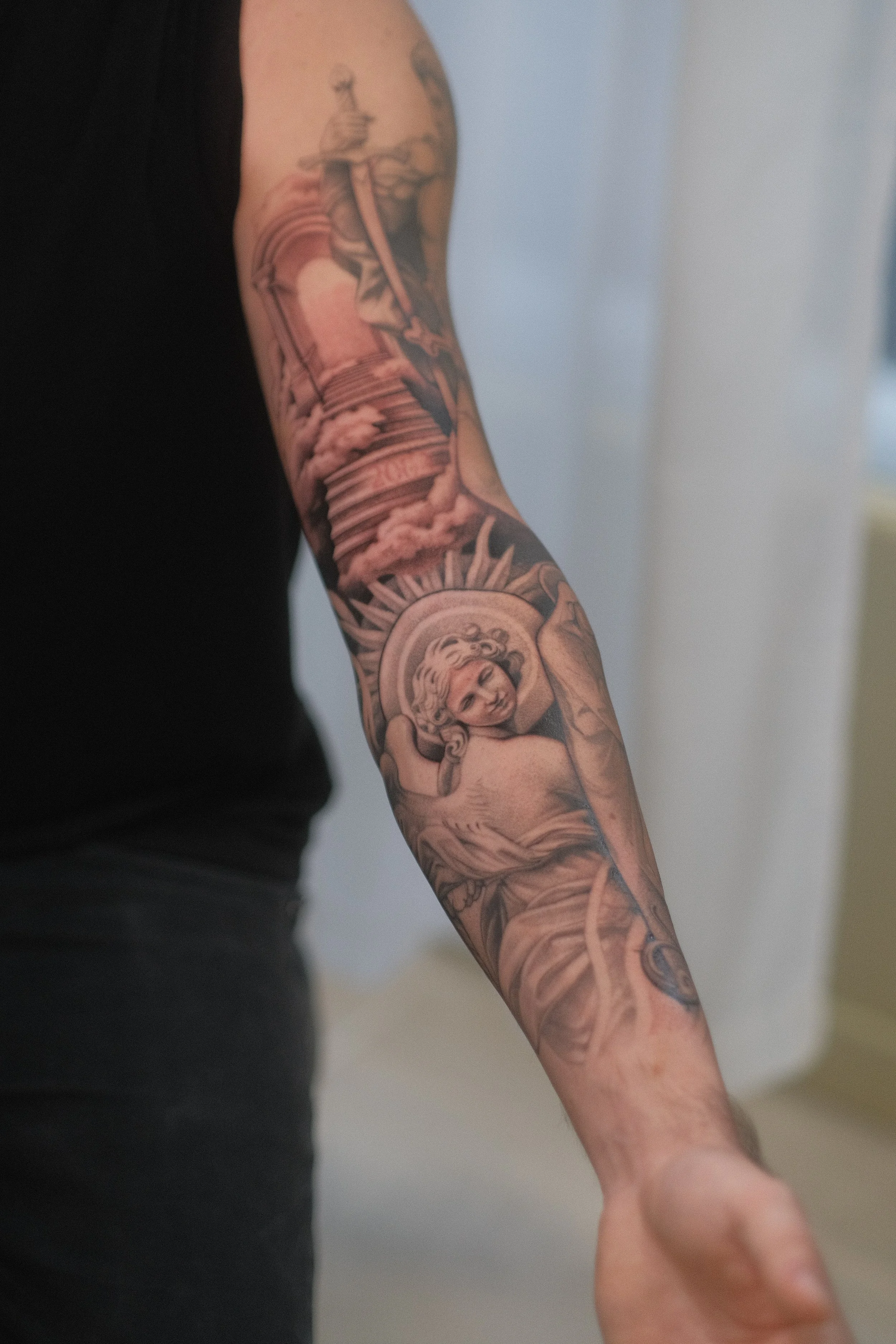 Gros plan sur un bras tatoué représentant une scène religieuse avec Jésus et une croix.