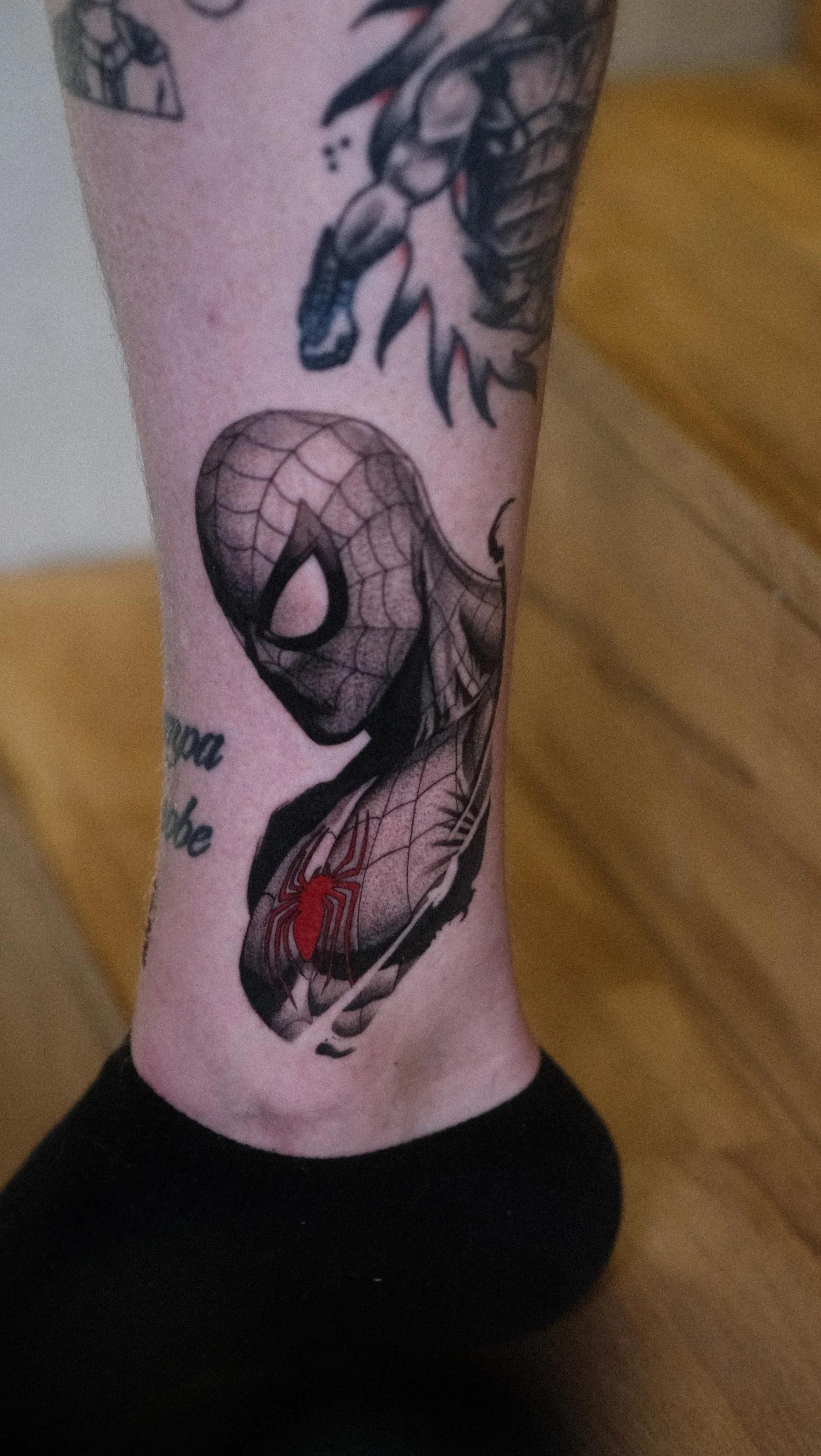 Gros plan d’un tatouage de Spider-Man sur un bras, avec une araignée rouge et noire sur le costume du super-héros.