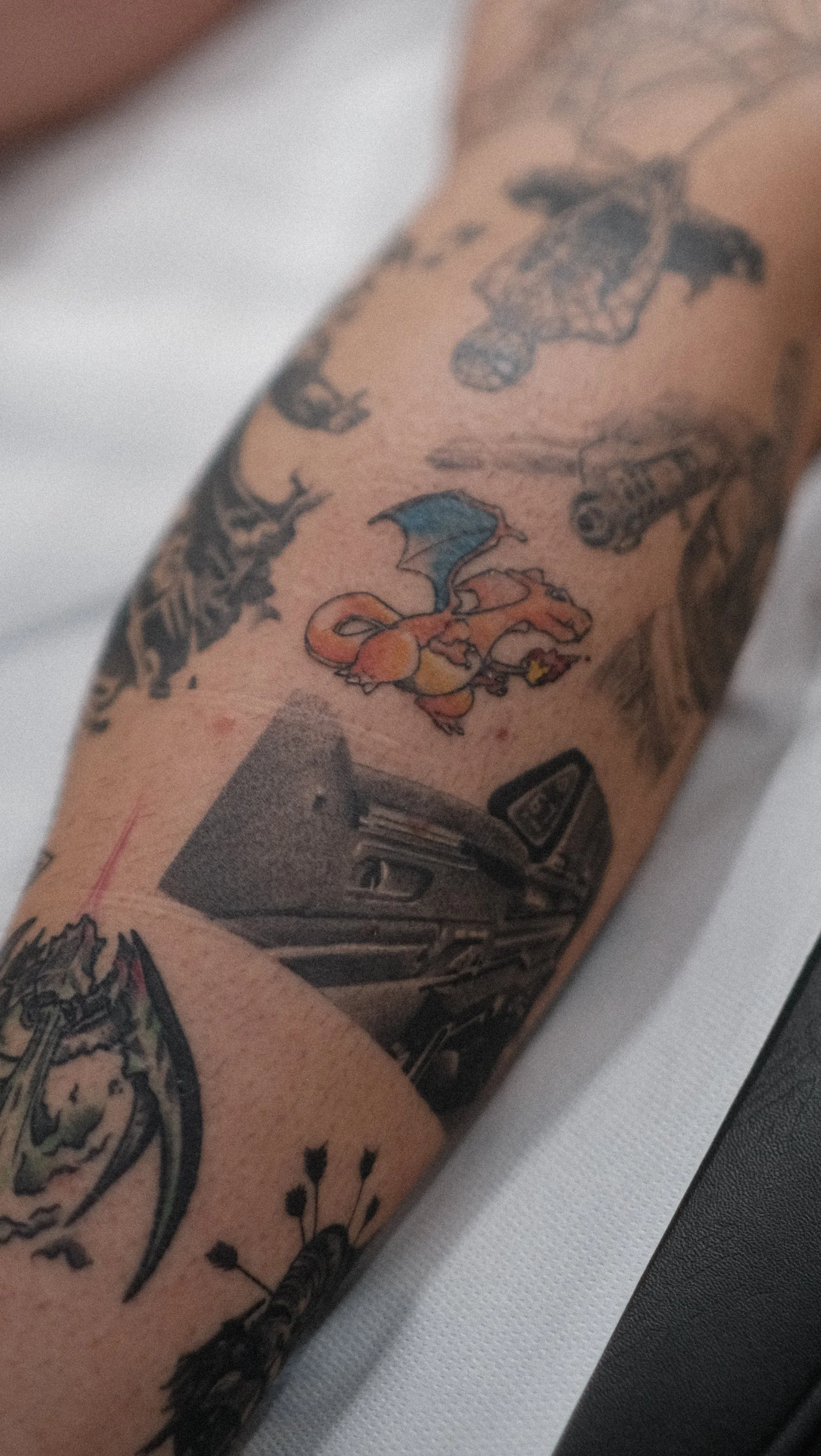 Gros plan d’un bras tatoué de motifs colorés, dont un personnage de dessin animé, avec un bracelet noir.