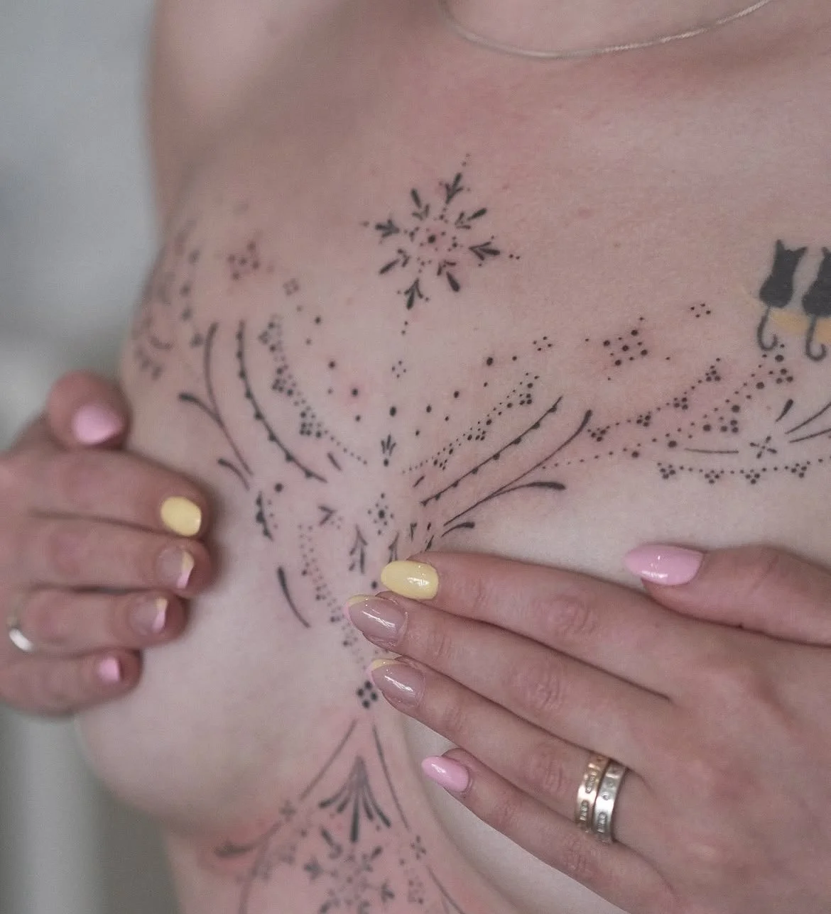 Gros plan d’un corset rose décoré de motifs floraux, tenu par des mains aux ongles pastel.