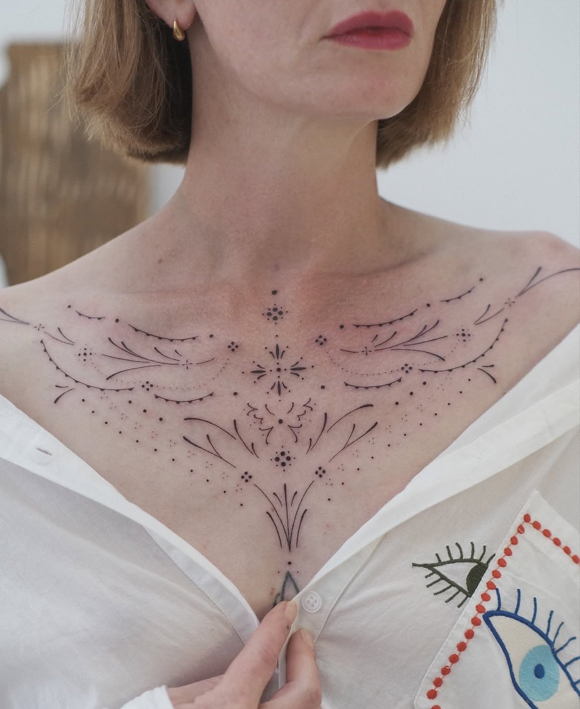 Gros plan sur une femme portant un tatouage floral géométrique sur le haut de la poitrine.